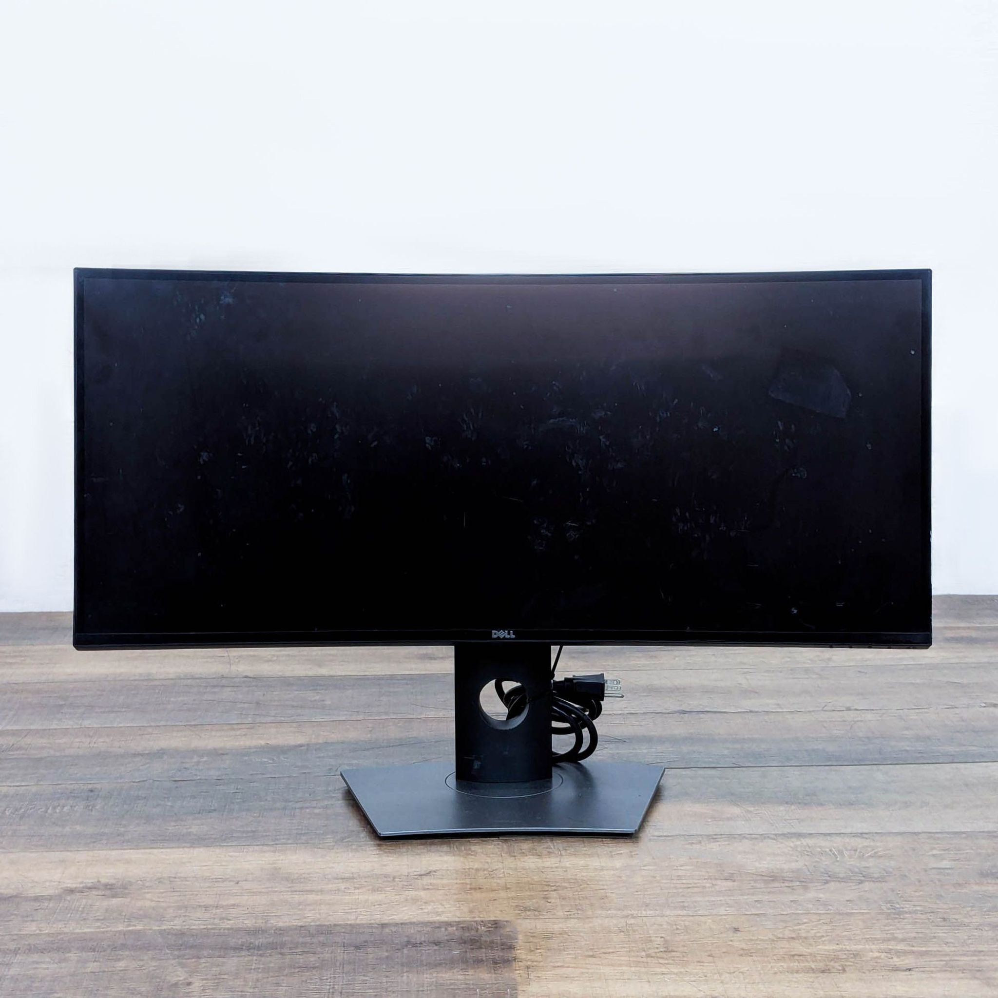 Dell curved monitor, front view on wooden table.