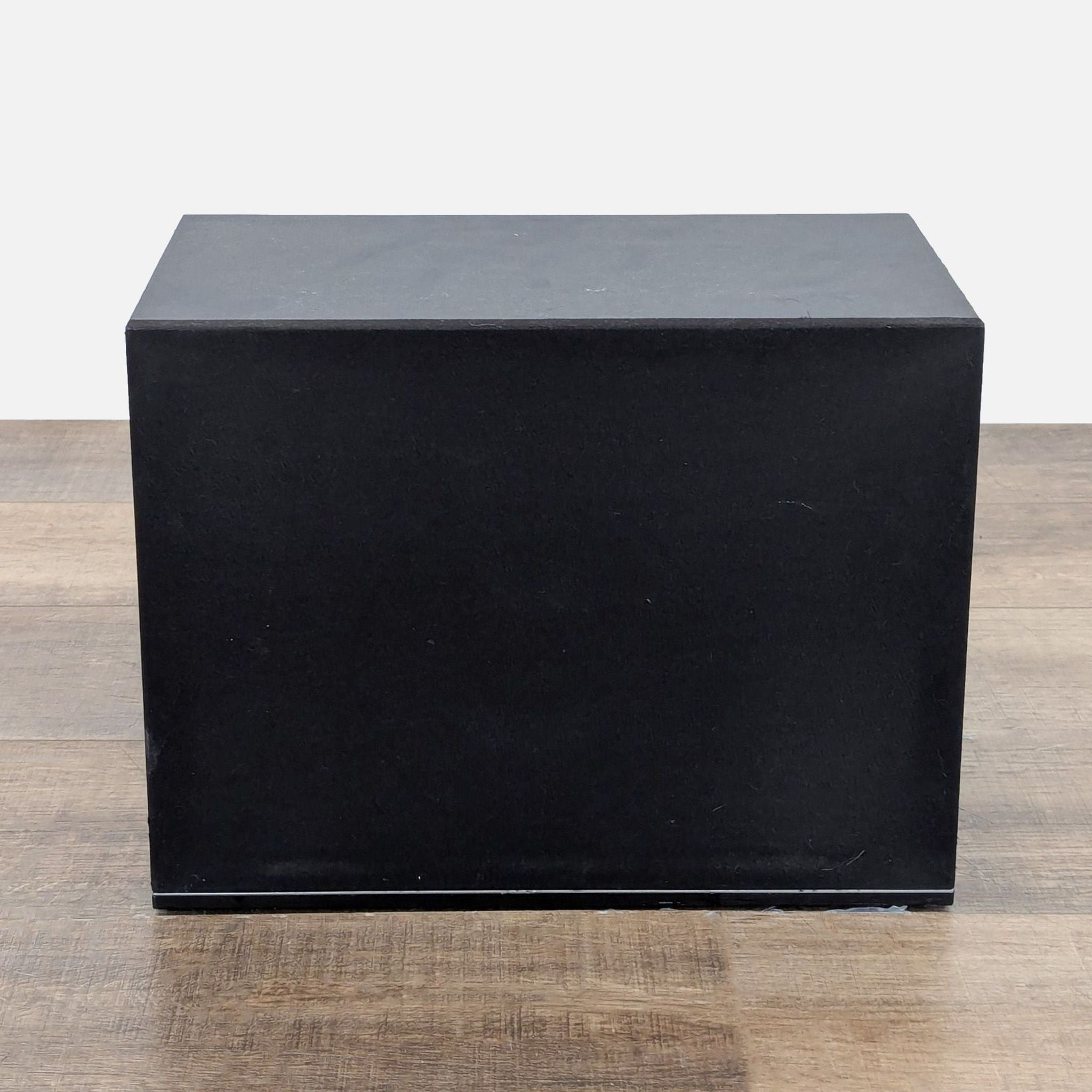 Close-up of the Vizio subwoofer, showcasing its sleek black design on a wooden surface.