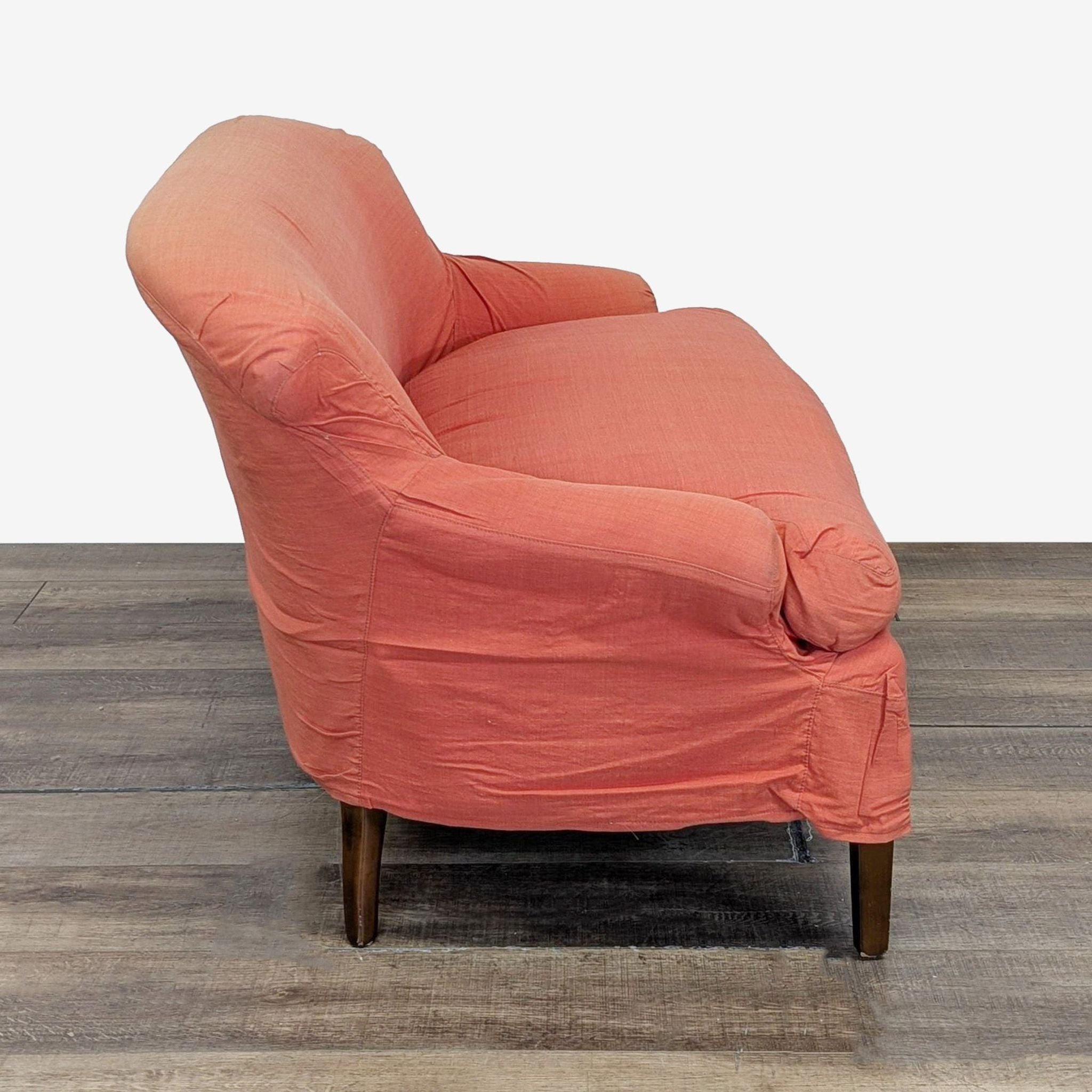 2. Side profile of a coral Chippendale loveseat with slipcover, showing curved arms and dark wood legs.  