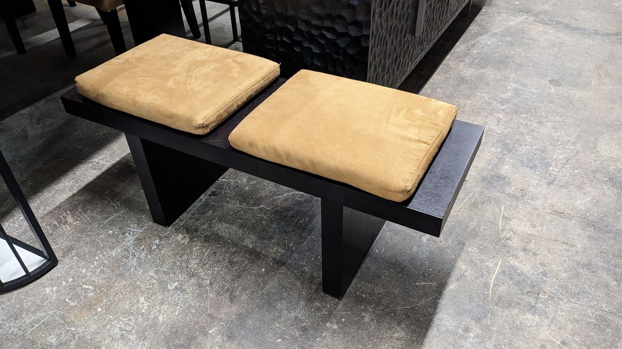 Reperch brand modern bench with two tan cushions on a black base displayed on a concrete floor.