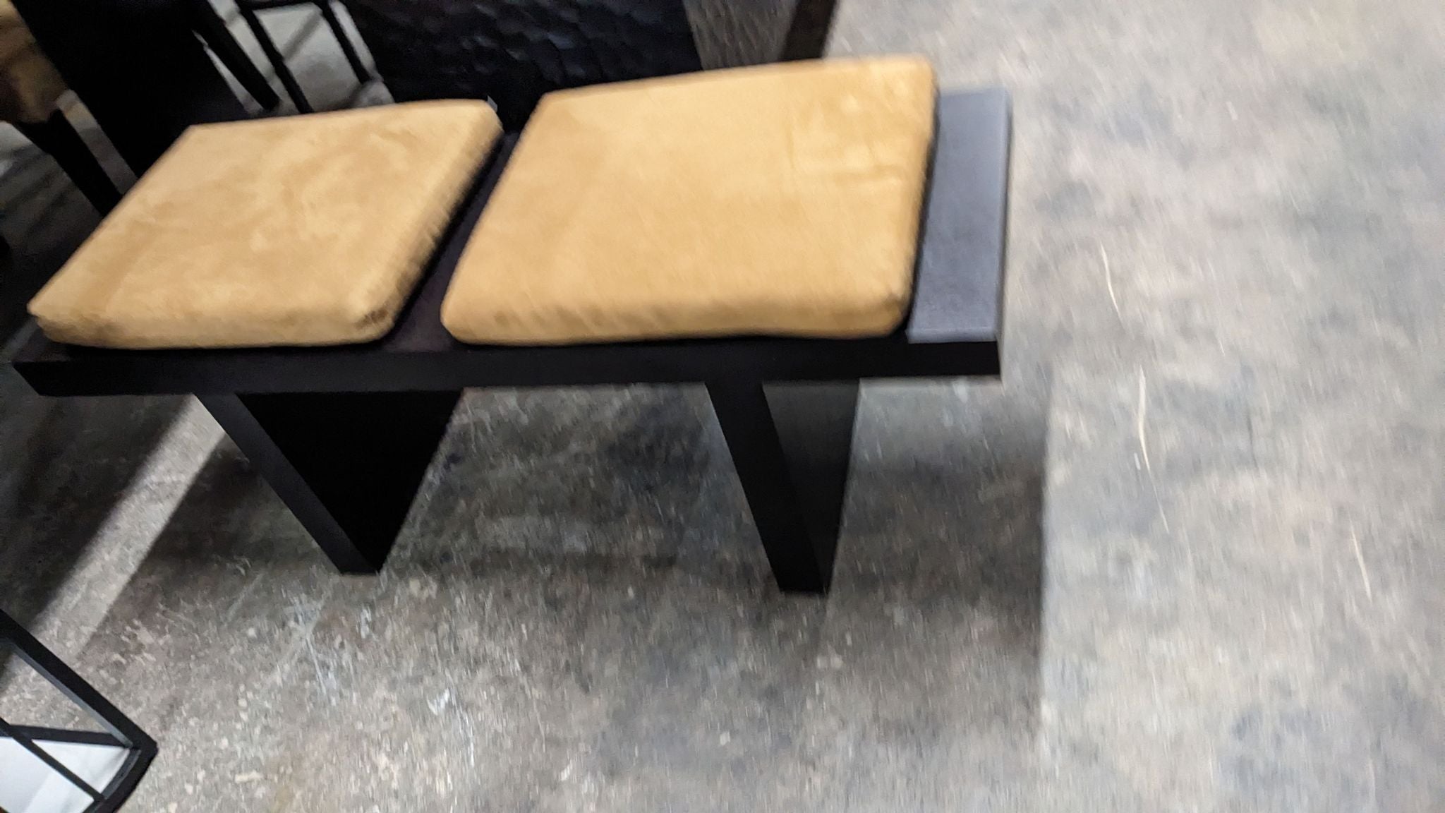 Alt text 1: A modern Reperch bench with two golden tan cushions on a black base, displayed in a furniture store.