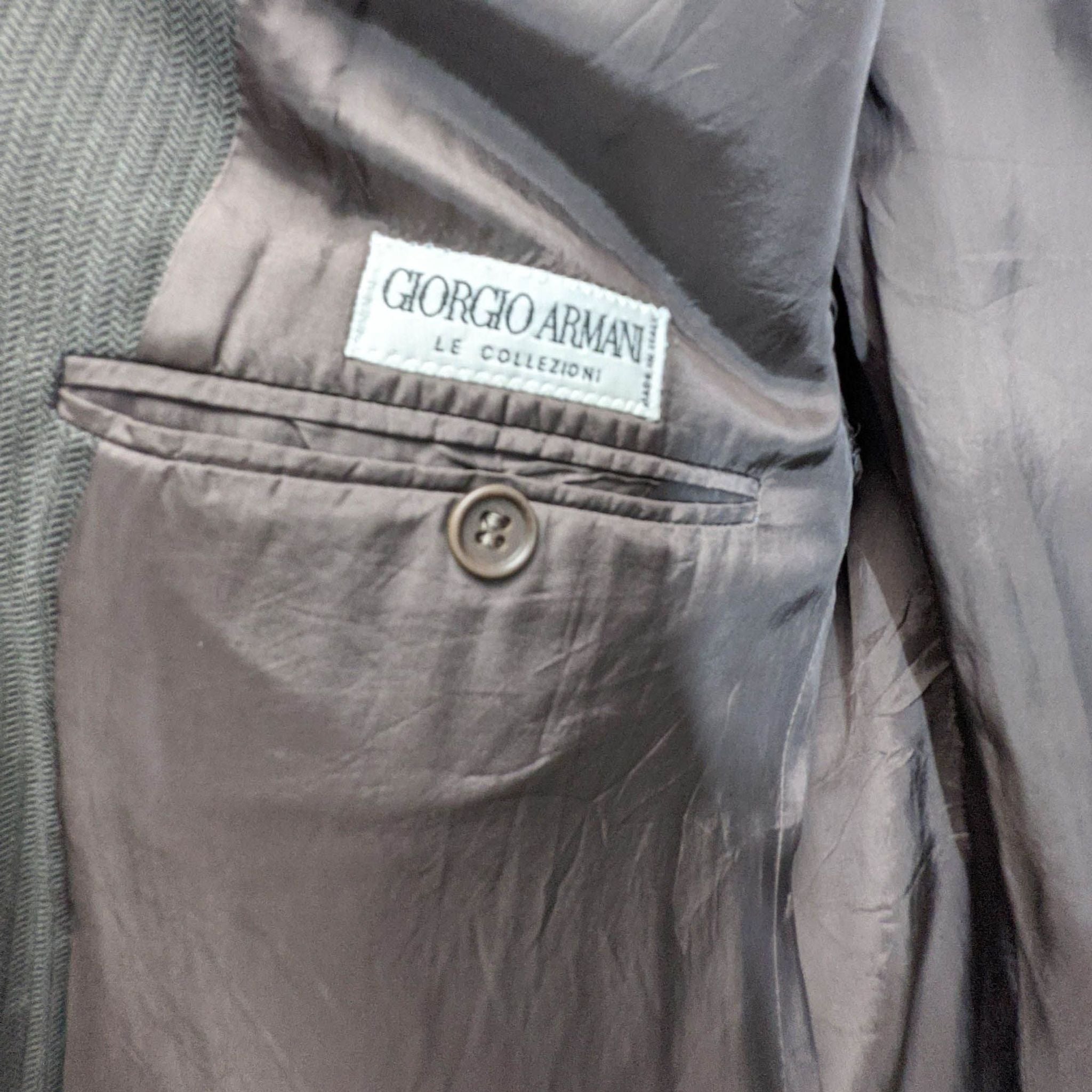Close-up of a Giorgio Armani label on a men's grey suit with a buttoned pocket.