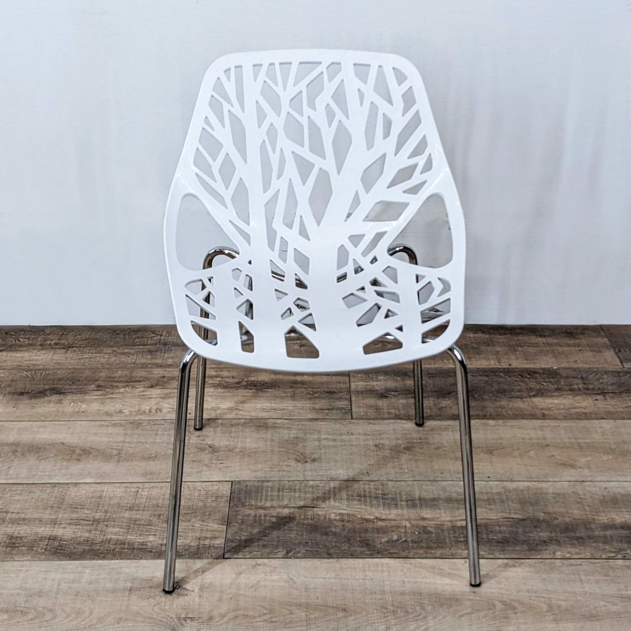 White Reperch dining chair with a tree branch-like backrest design and chrome legs, on wooden flooring.
