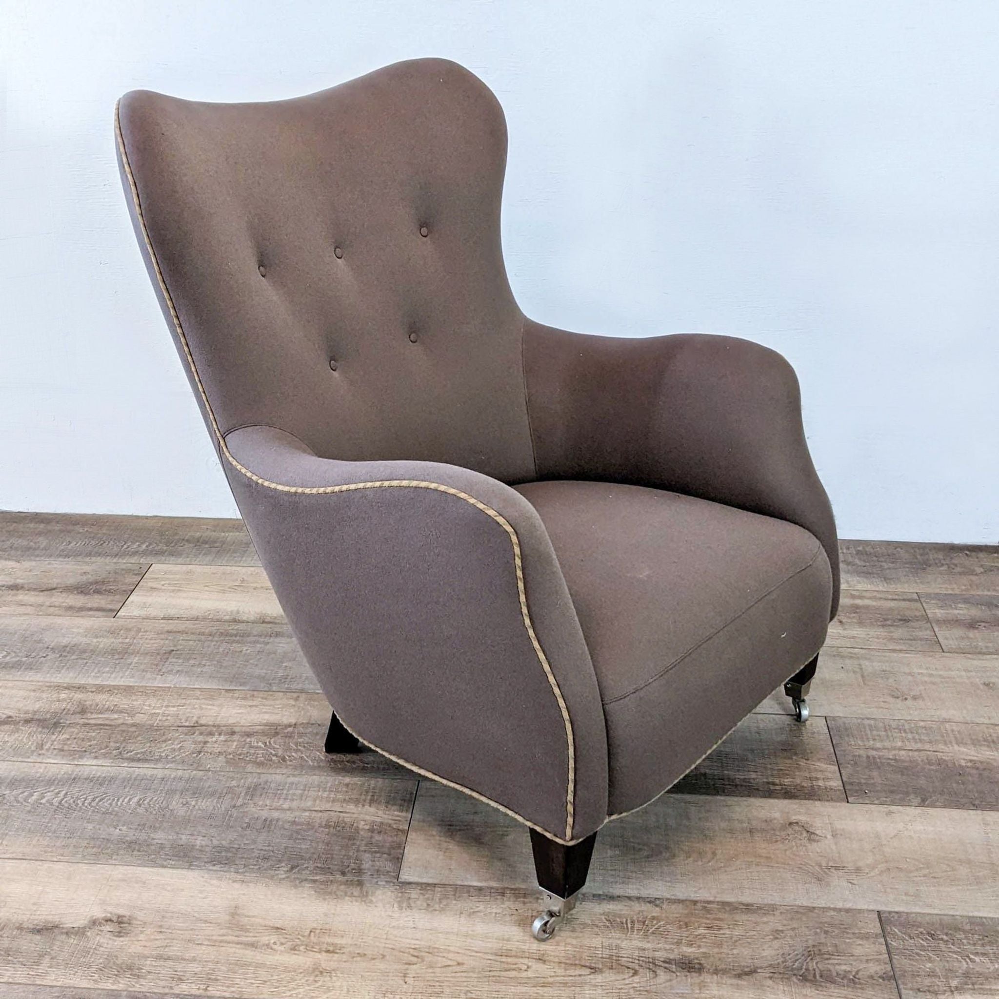 Alt text 2: A single RomI mini lounge chair by Cisco Brothers, showcasing its tufted back, contrasting piping, and boot casters against a simple backdrop.