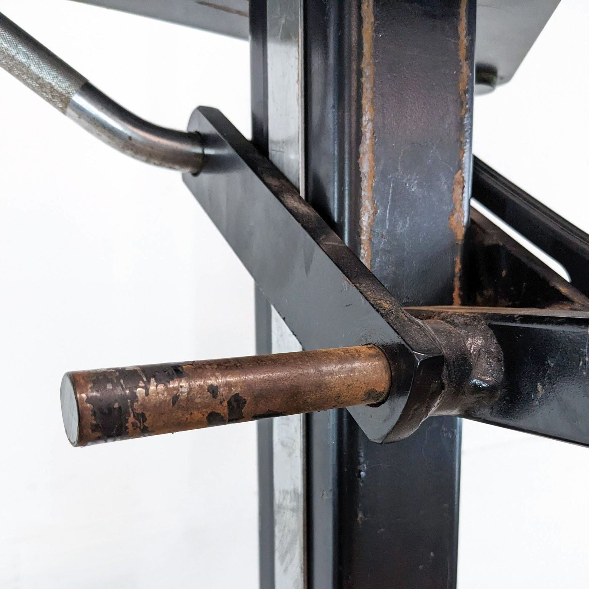 Close-up of a worn Soloflex gym equipment part with metal bars and joints.