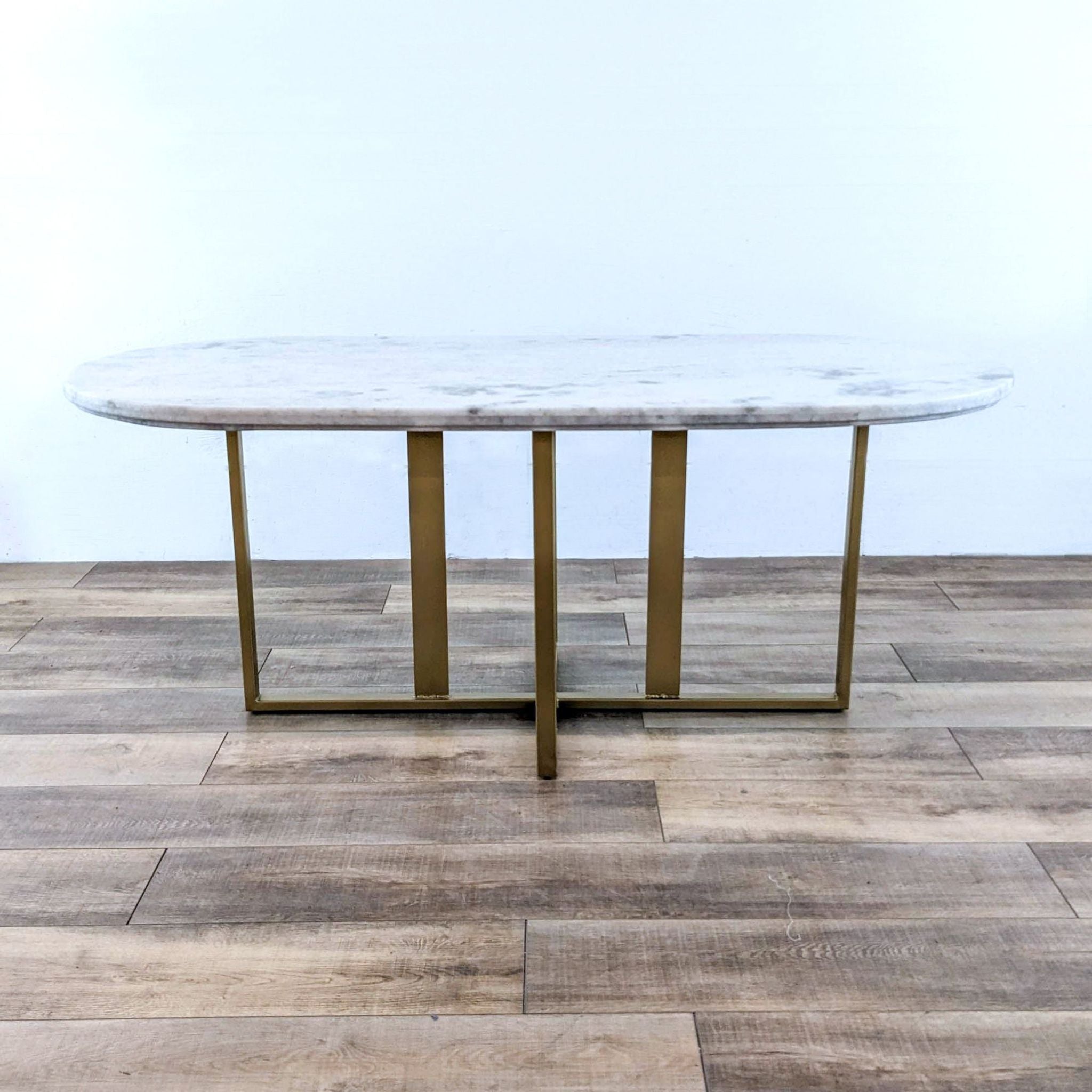 Alt text 1: The Dylia dining table by Four Hands, featuring a brass-finished iron base and a round white marble top, on a wooden floor.