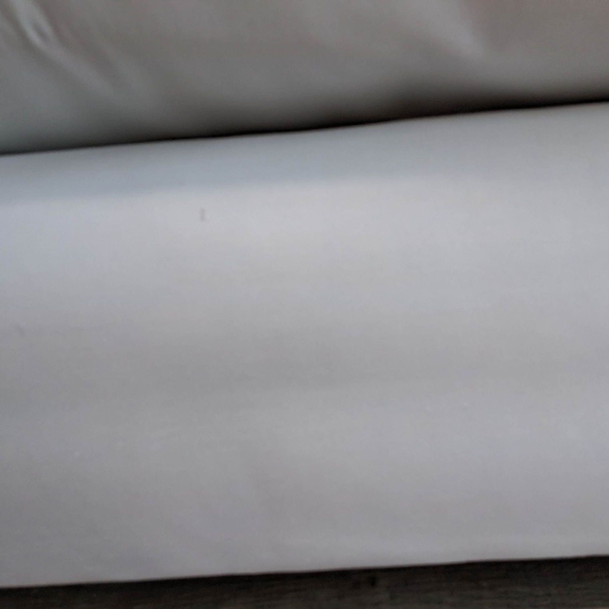 Close-up of a white classic slipcover fabric for a Reperch brand three-seat sofa.