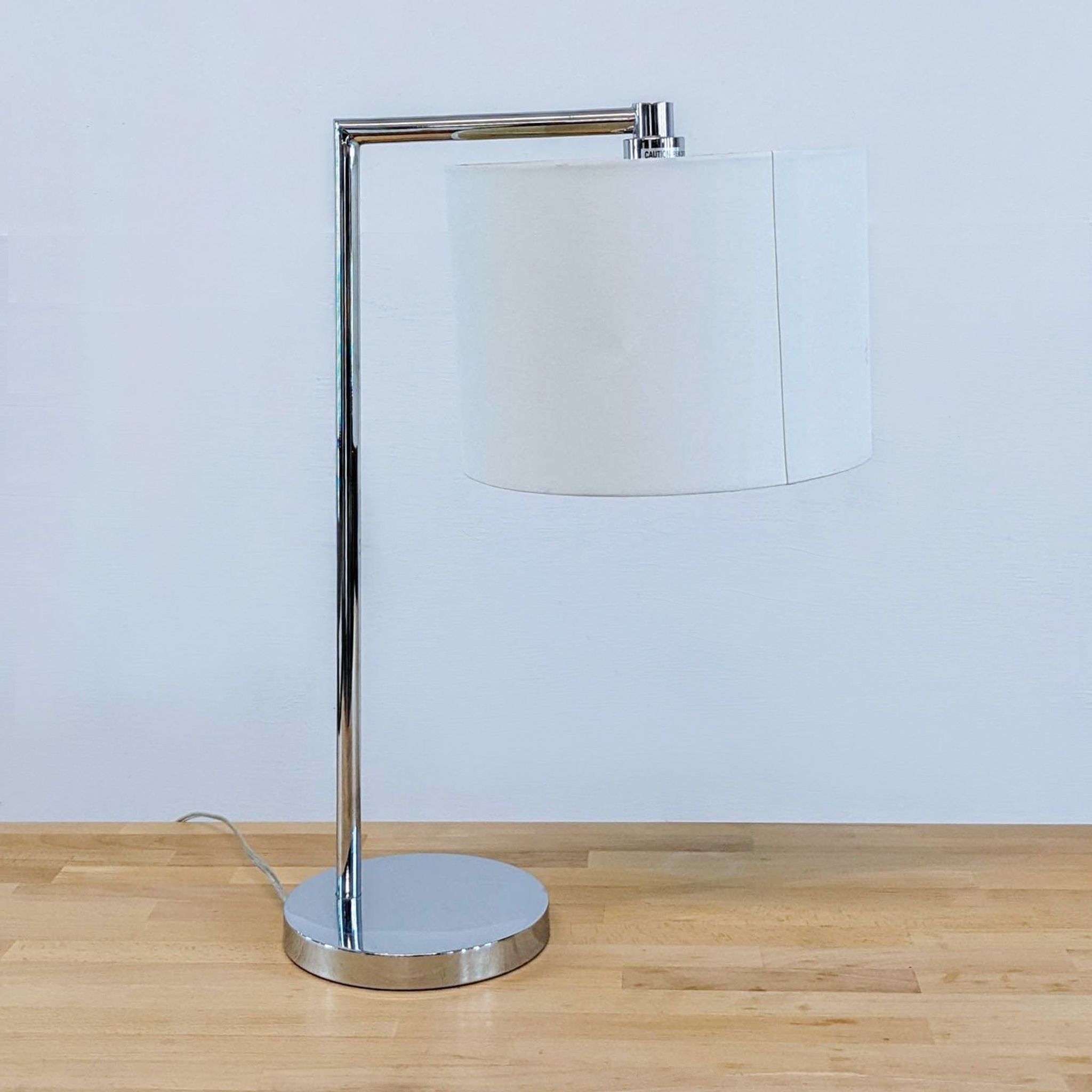 Modern Reperch lamp with a shiny chrome base and a white drum shade against a plain background, off state.