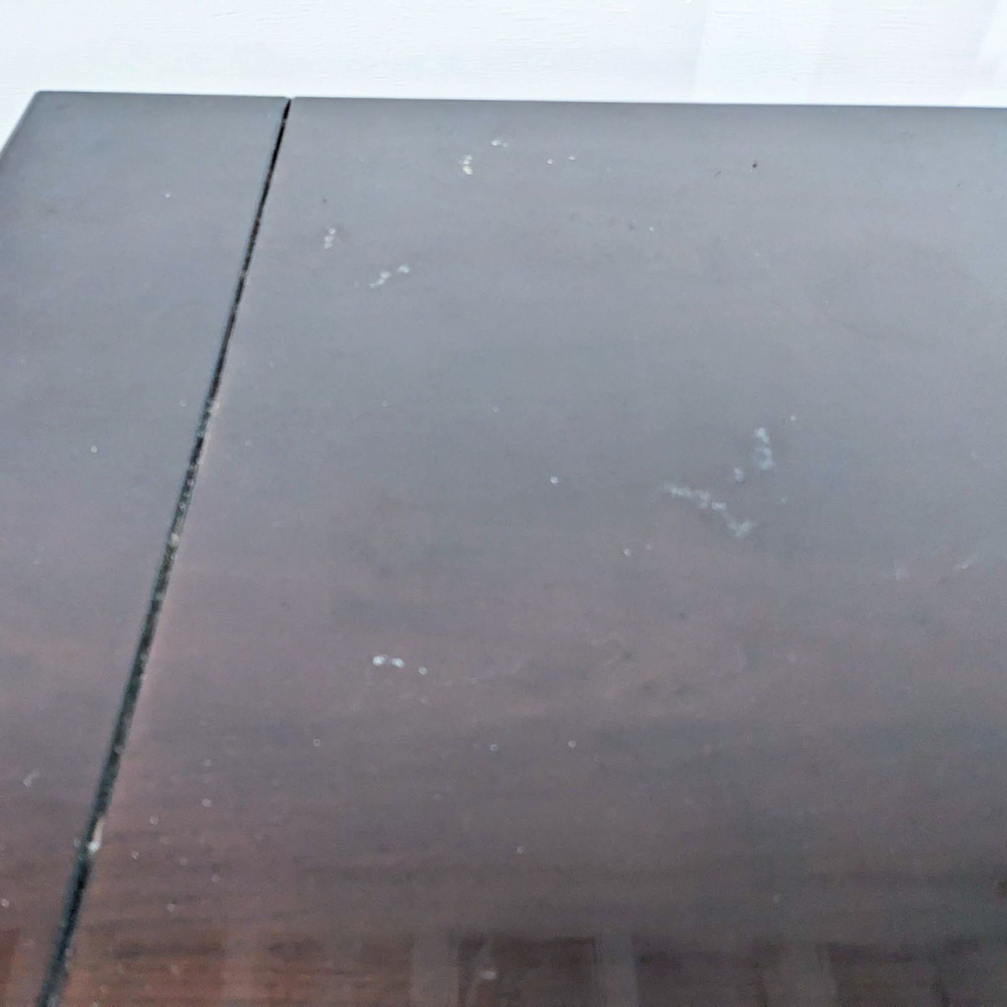 Close-up of a dark brown Universal Furniture sideboard top with visible wear and scratches.