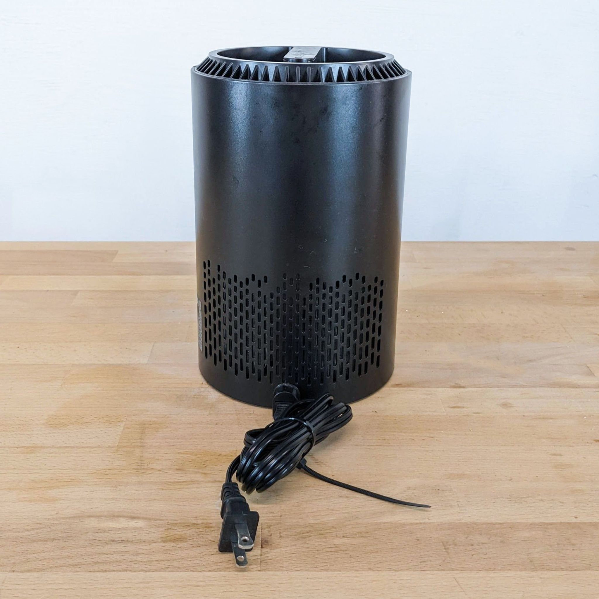 Alt text 2: Black Reperch device with power cord, vented top, and perforated design, displayed on wooden table.