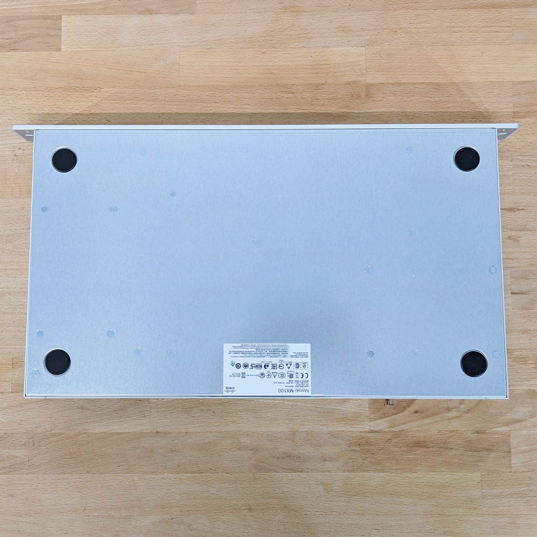Cisco networking product top view placed on wood, showing a grey metal case with label details.
