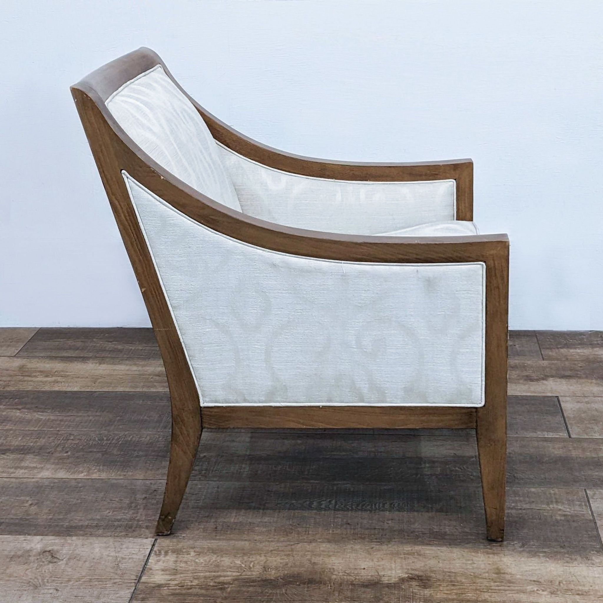 Side angle of H.D. Buttercup lounge chair showing wood frame and patterned white upholstery with a focus on the chair’s armrest.