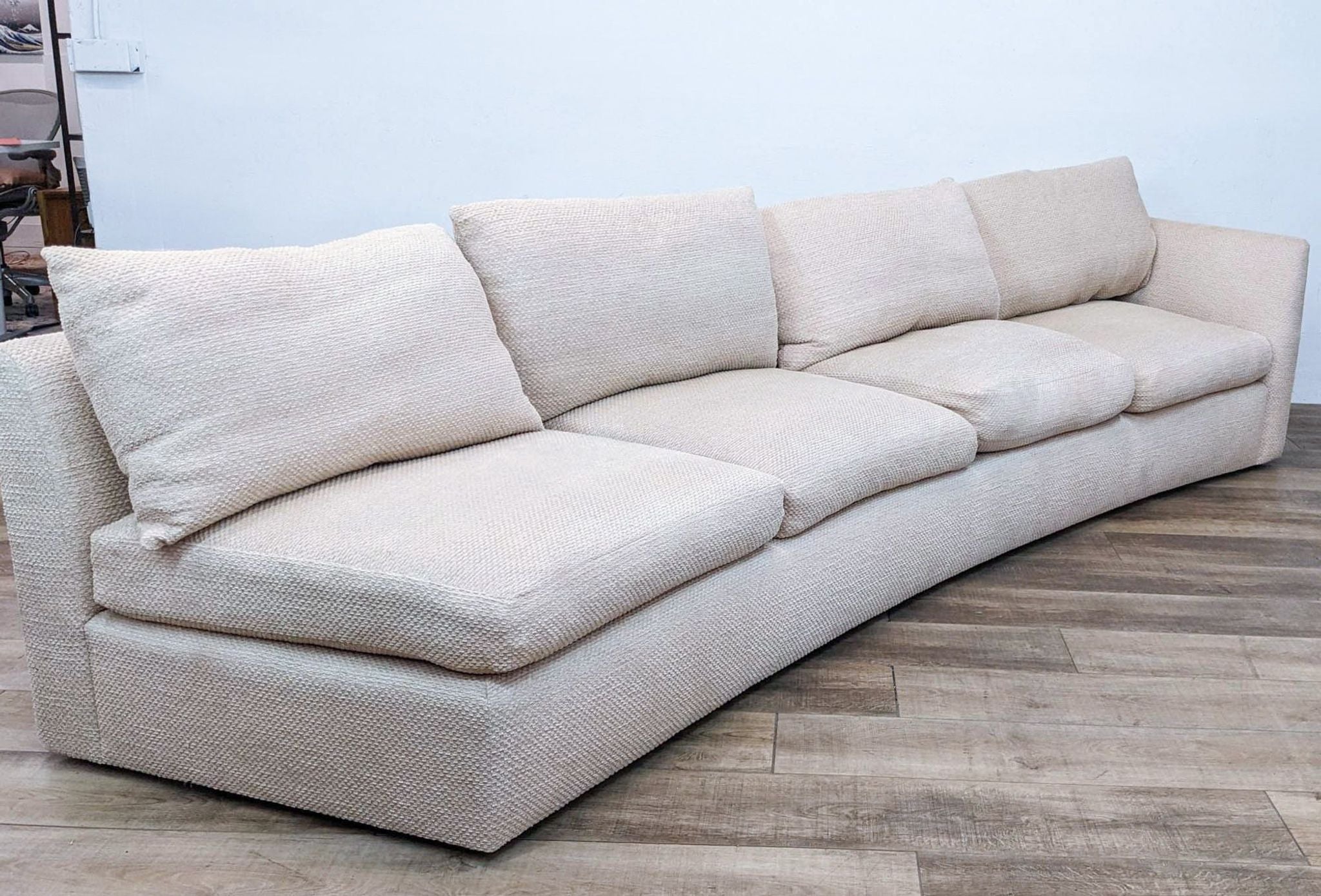 Beige one-piece sectional with unique curved design by Reperch, angled view showcasing shape.