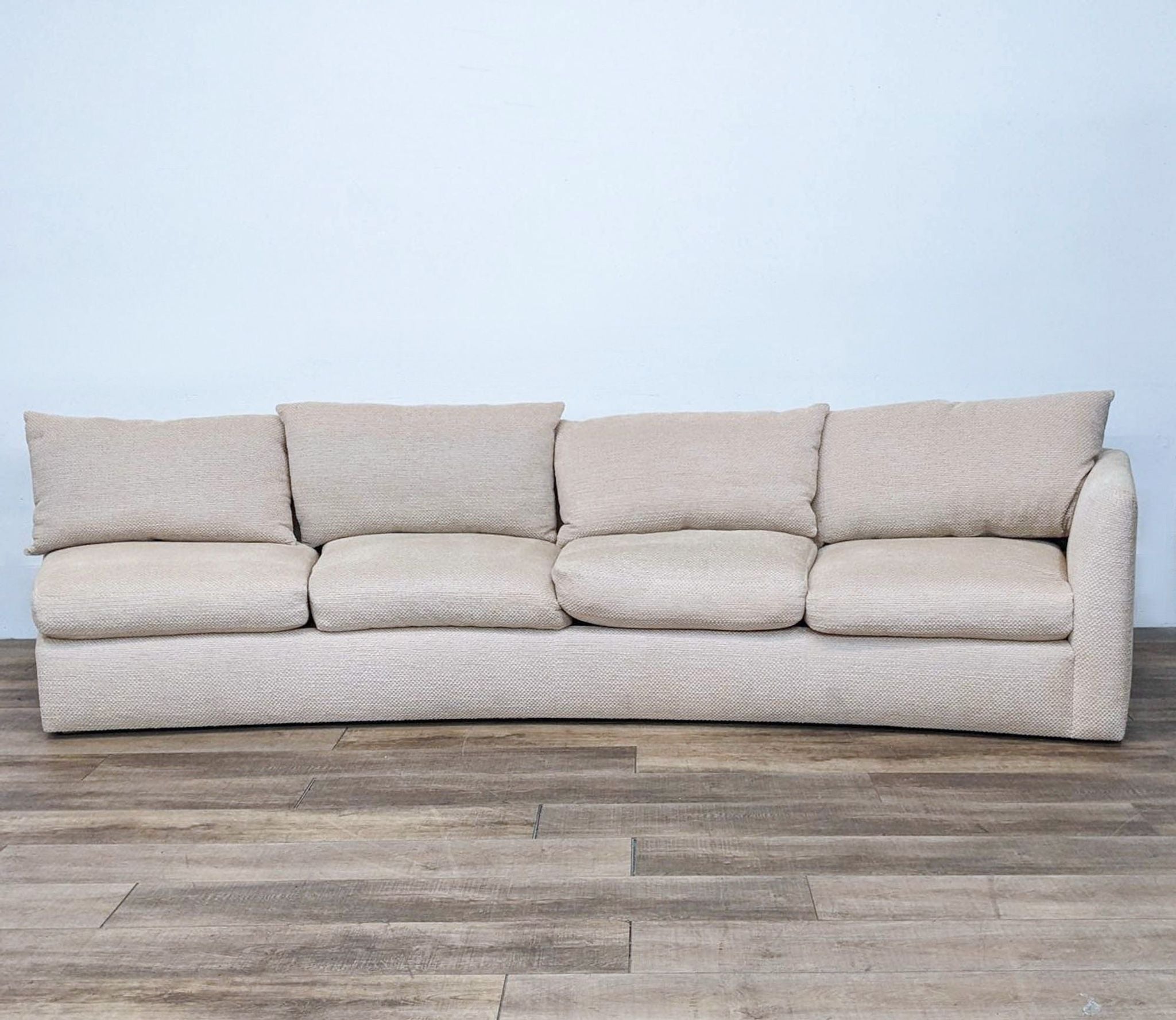 Large one-arm curved sectional sofa by Reperch, beige fabric, front view on wooden floor.