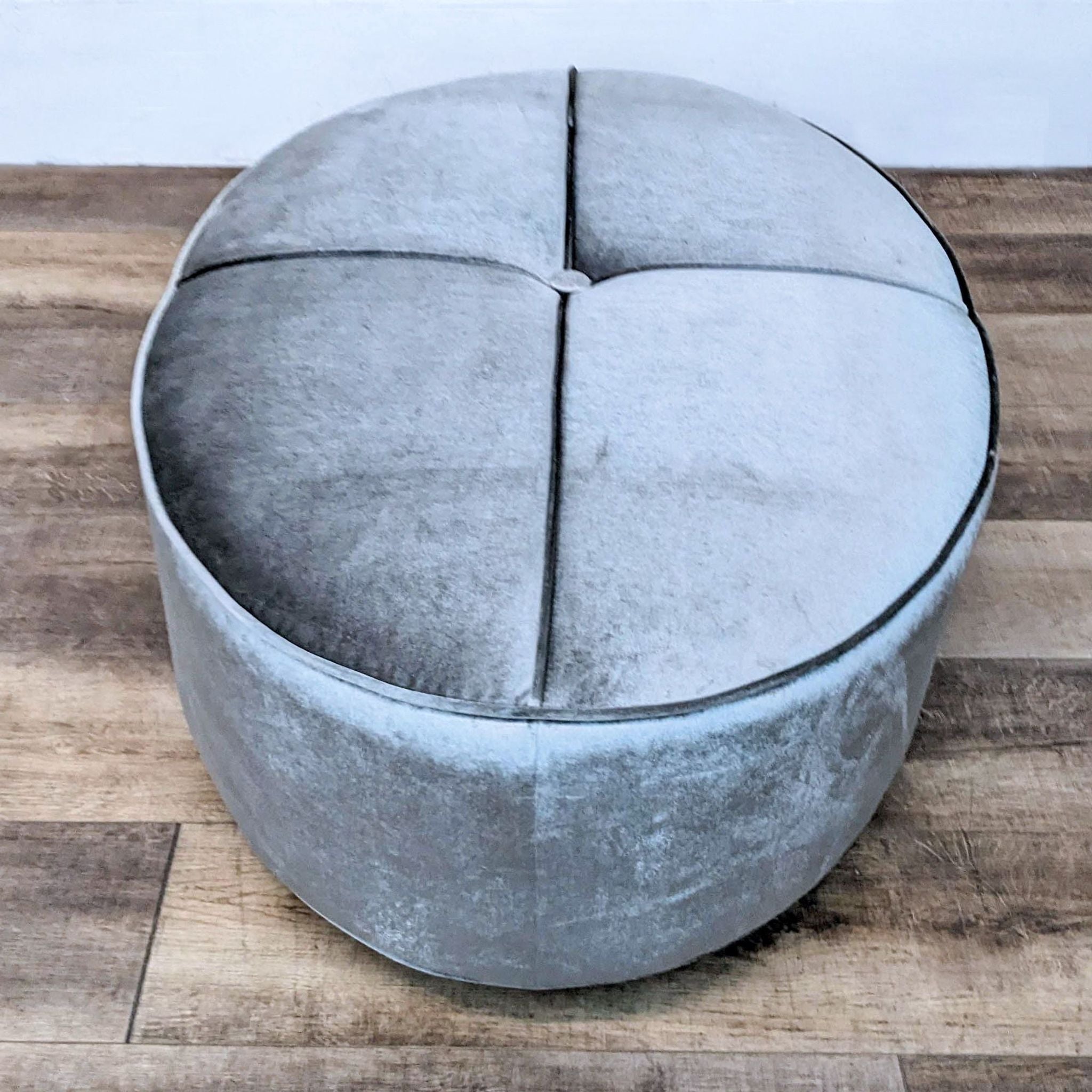 Coaster brand ottoman featuring sleek oval shape, piping detail, and metal-look base.