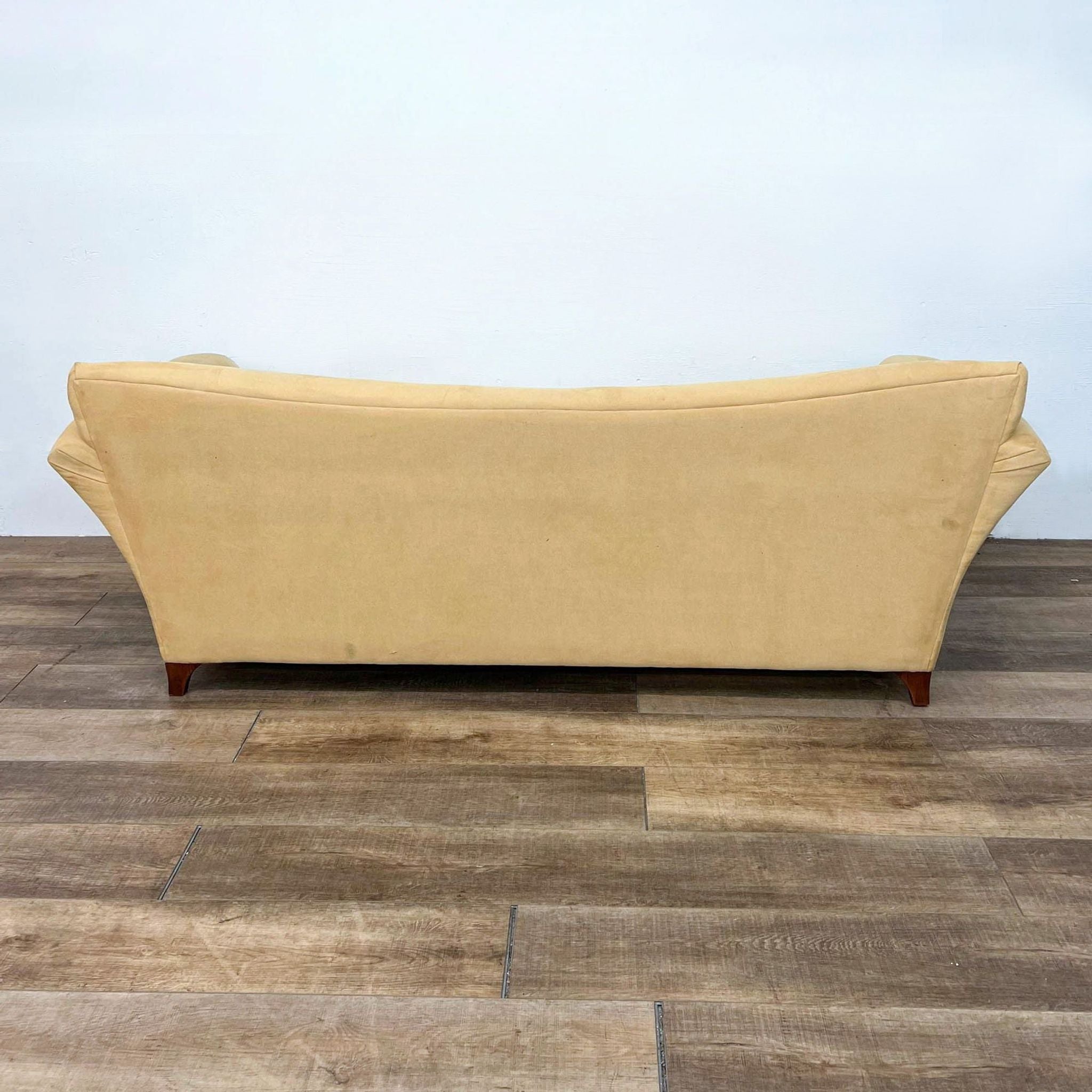 Alt text: Rear view of a Reperch brand 3-seat flared arm straight back sofa with wooden feet on a wooden floor.