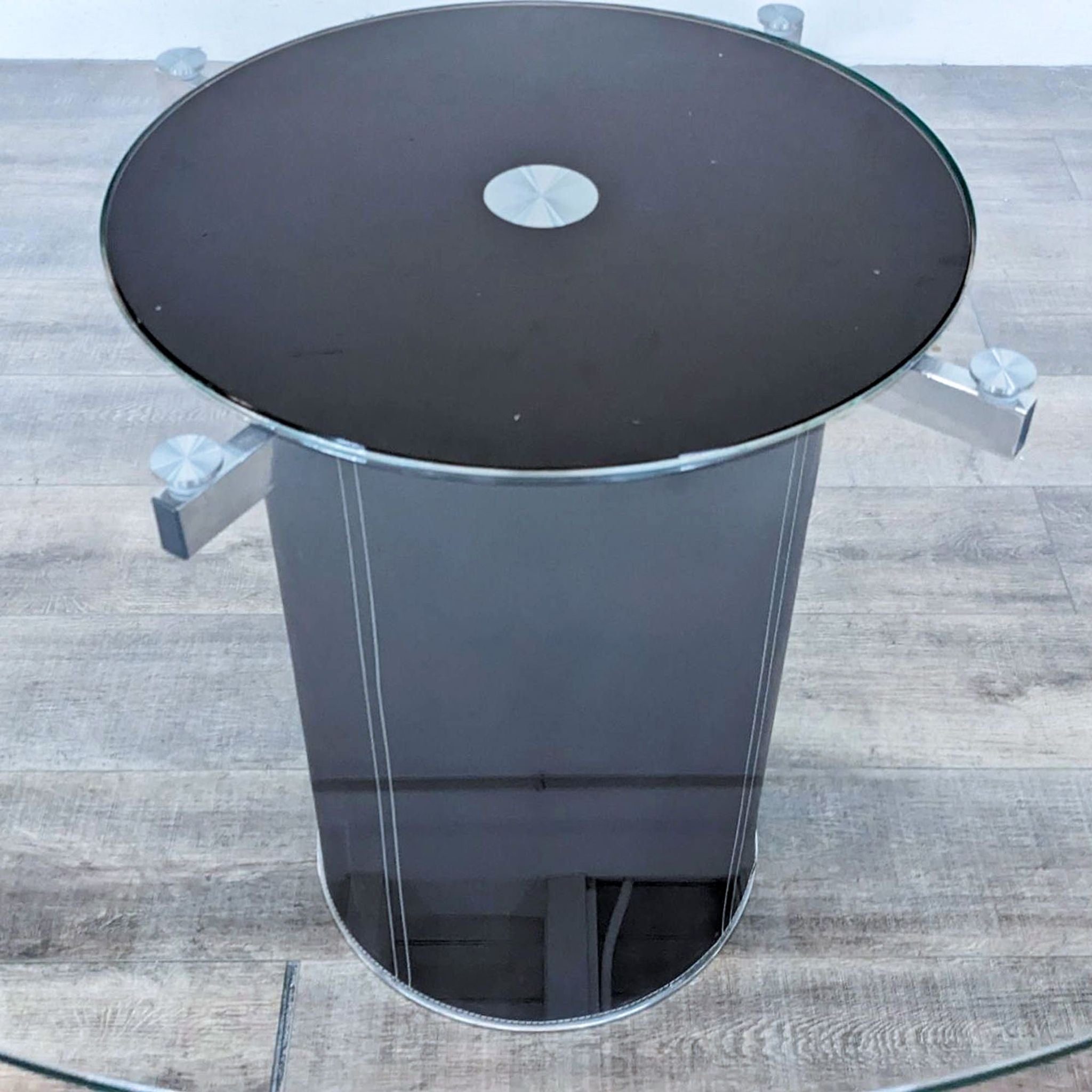 Scandinavian Designs Lauss table featuring a round glass top with a 360° spinning tray and a sleek base of steel and regenerated leather.