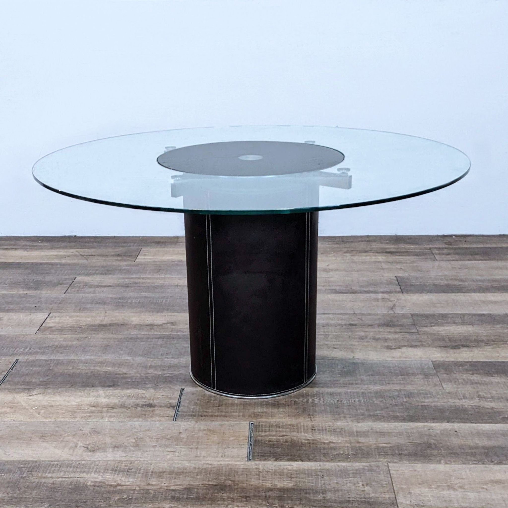 Round Lauss dining table from Scandinavian Designs with stainless steel base, leather wrap, and a revolving glass top.