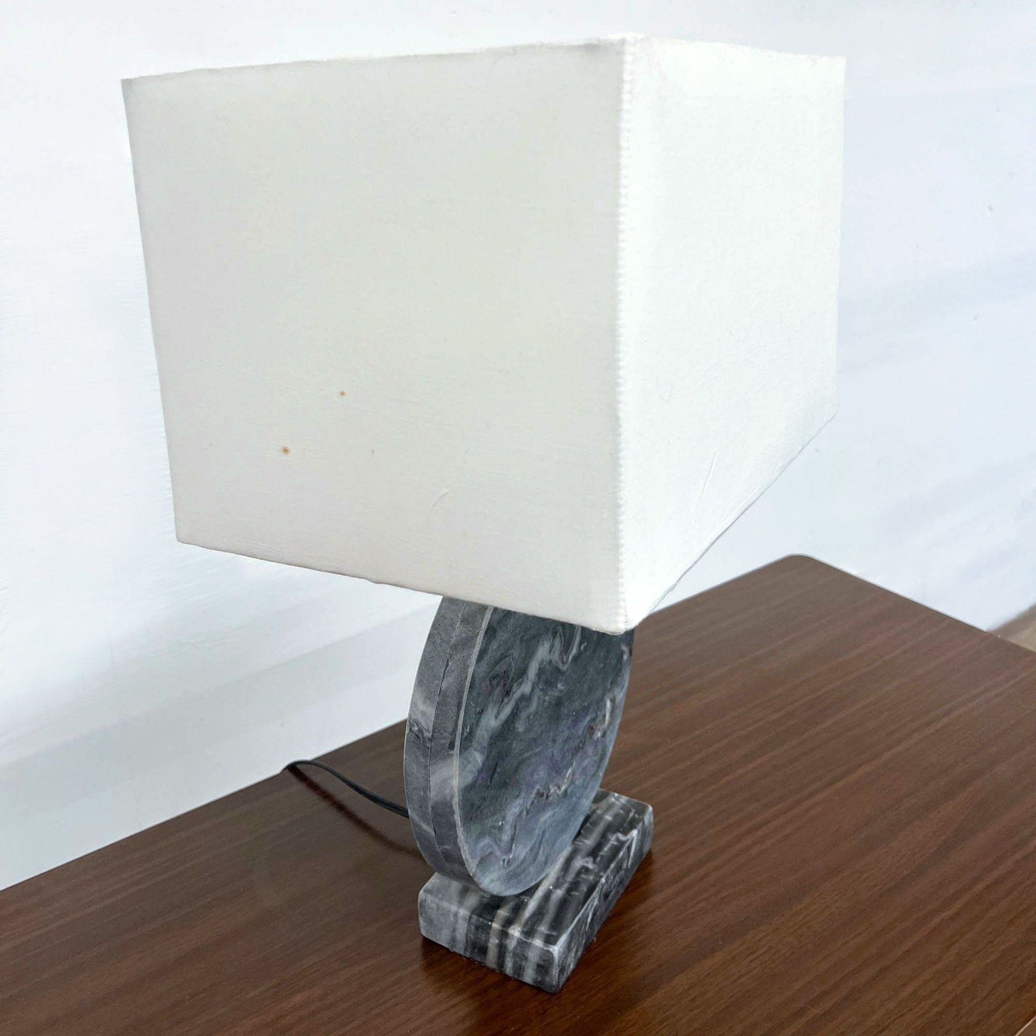 Reperch brand table lamp with square white shade and dark marble base, unplugged, on a wooden table.