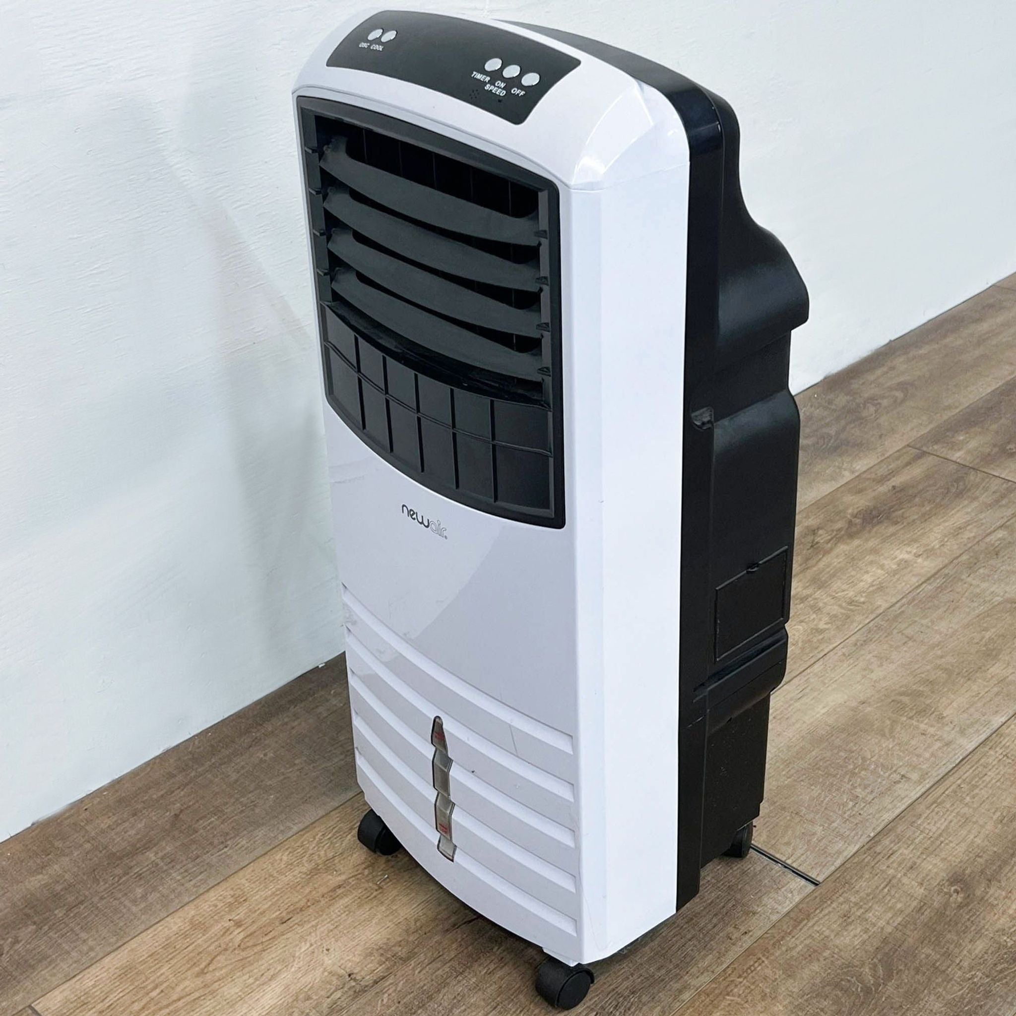 Alt text: NewAir portable air conditioner in white and black with control panel, on a wooden floor against a white wall.