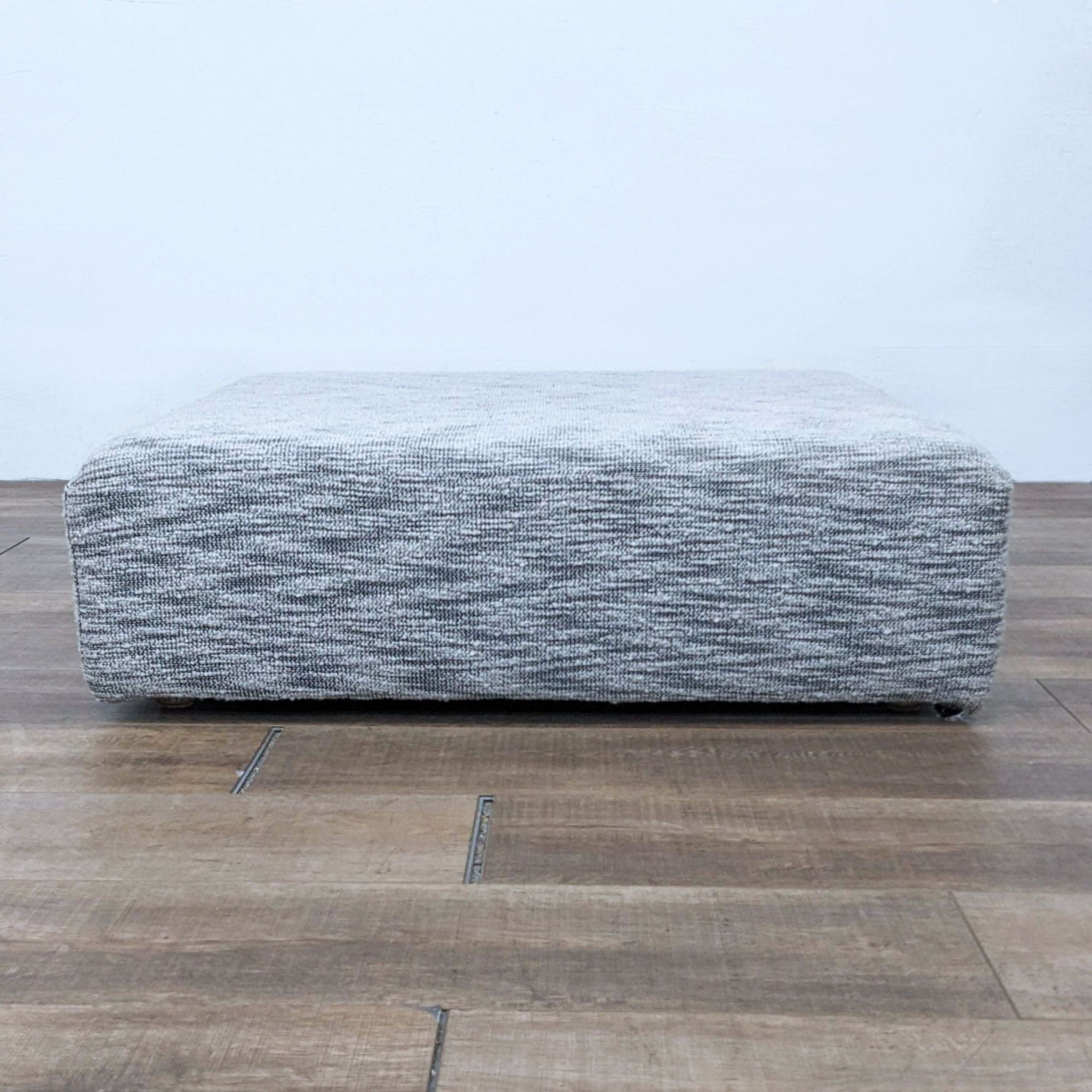 Restoration Hardware modern 40" square fabric ottoman with low profile and textured pattern on wooden floor.