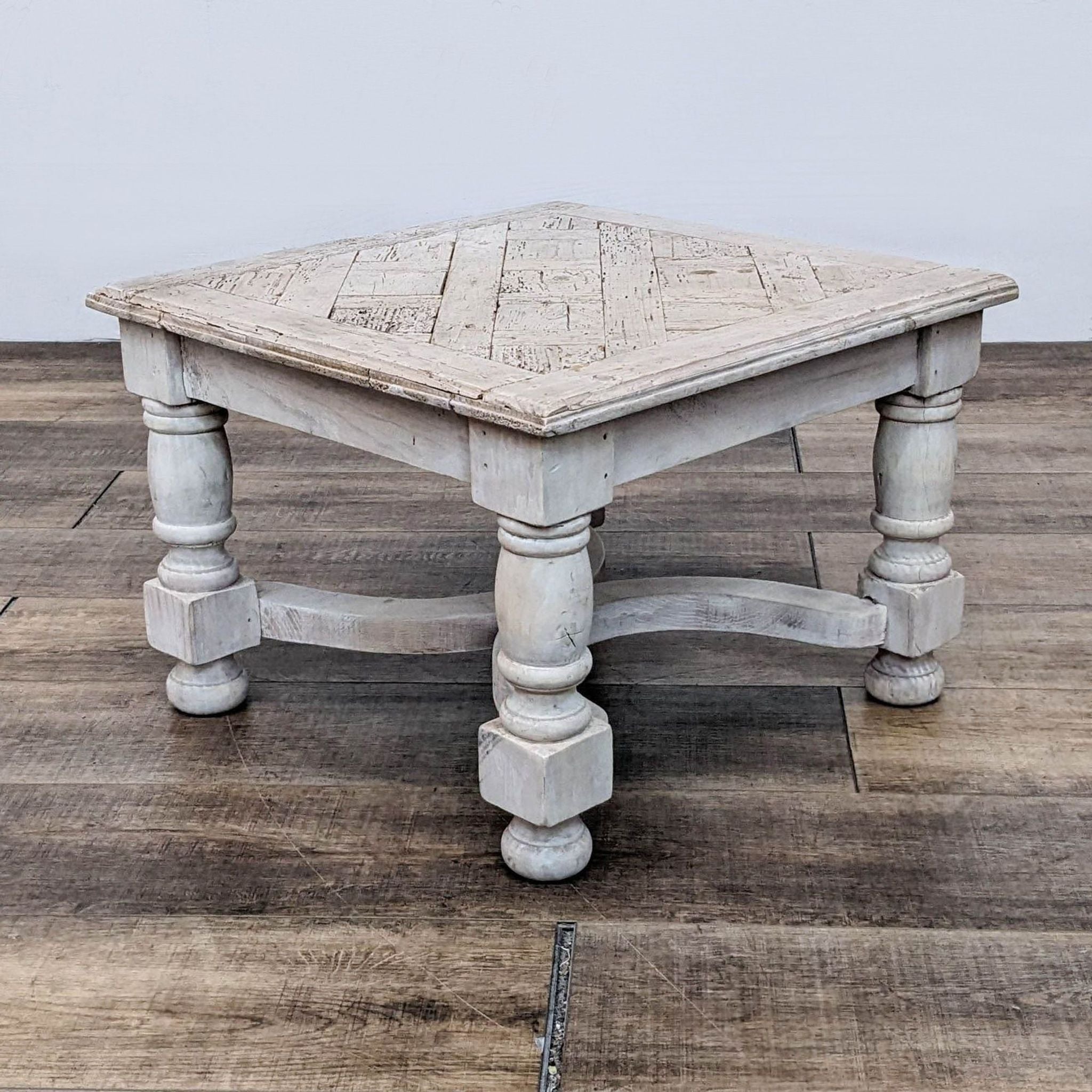 Distressed white square console table with geometric design and sturdy turned legs, by Reperch, shown in a room.