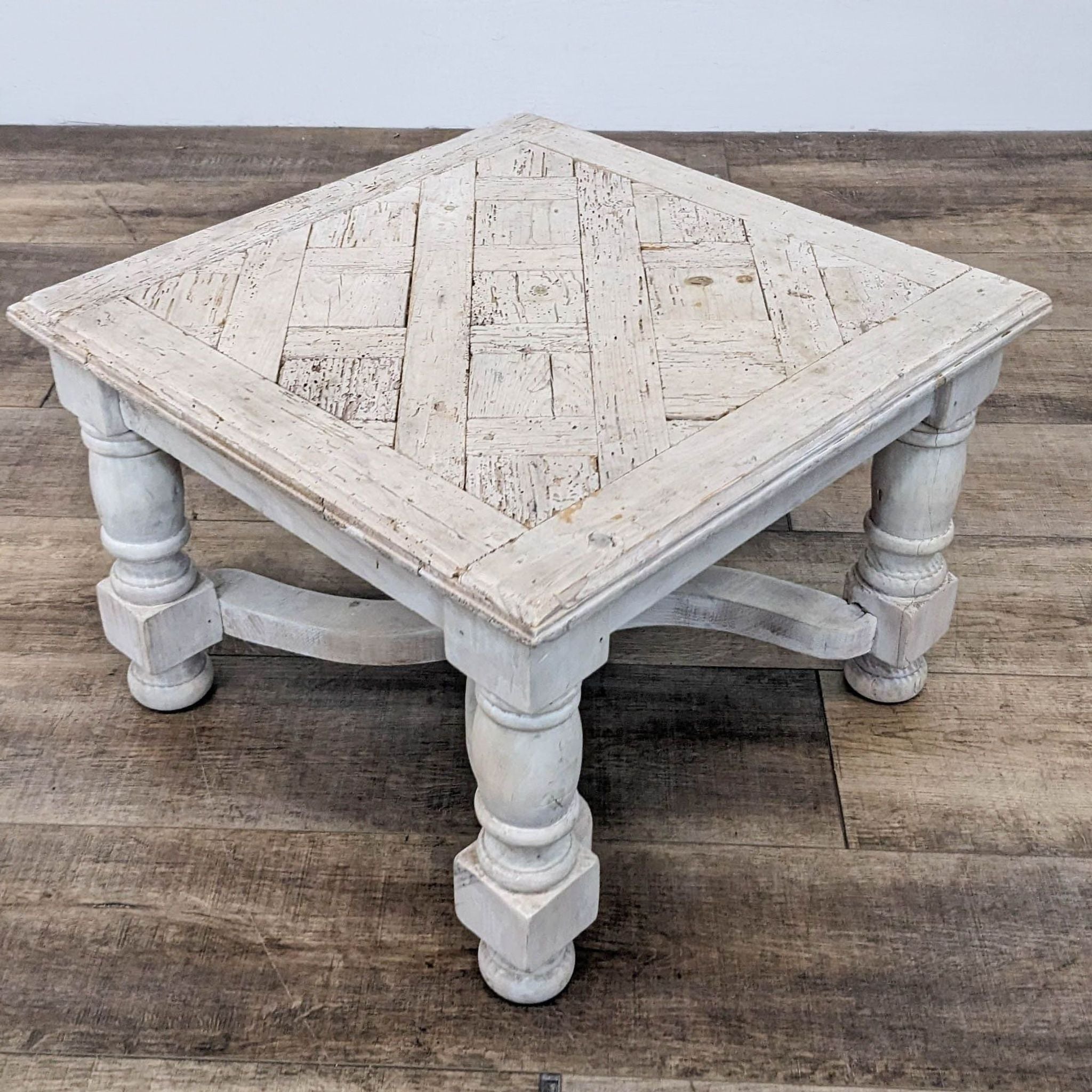 Reperch brand distressed white wooden side table with a square top and turned legs on a wooden floor.