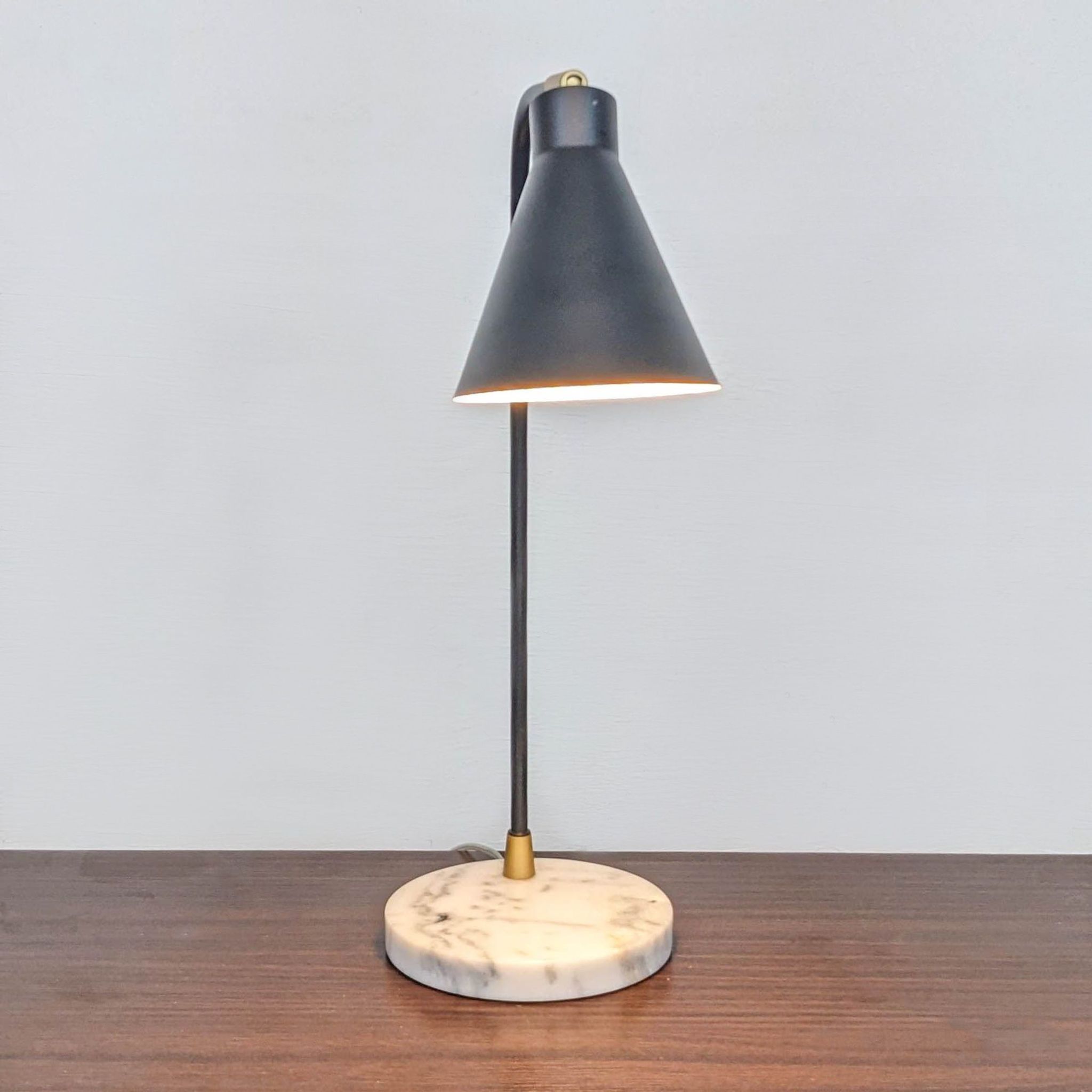 Reperch black desk lamp with cone-shaped shade and marble base on wooden surface, illuminated.