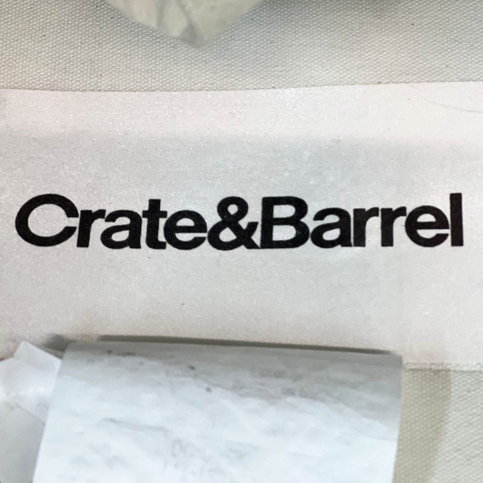 Close-up of Crate & Barrel logo on beige canvas slipcover material. 