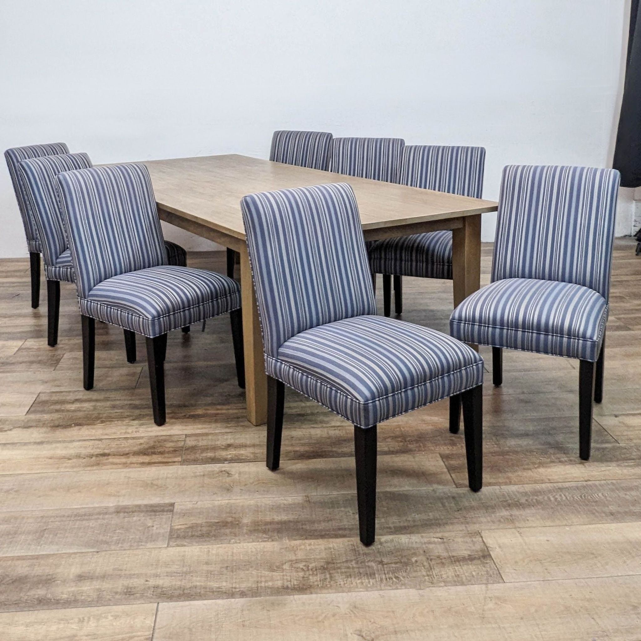 Reperch 9-piece dining set with natural wood finish table and striped upholstered chairs.