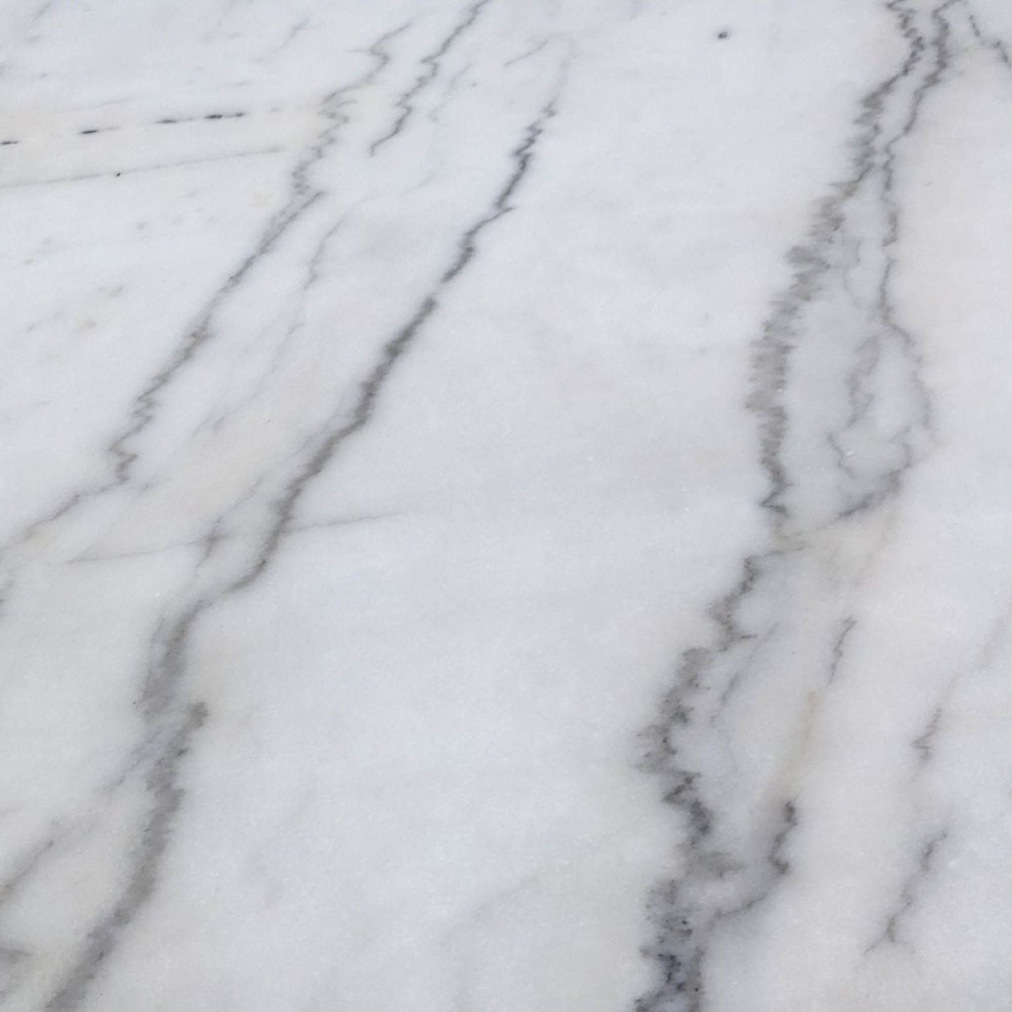 Close-up of white marble tabletop with grey veining, part of a Mitchell Gold Bob Williams modern dining table.
