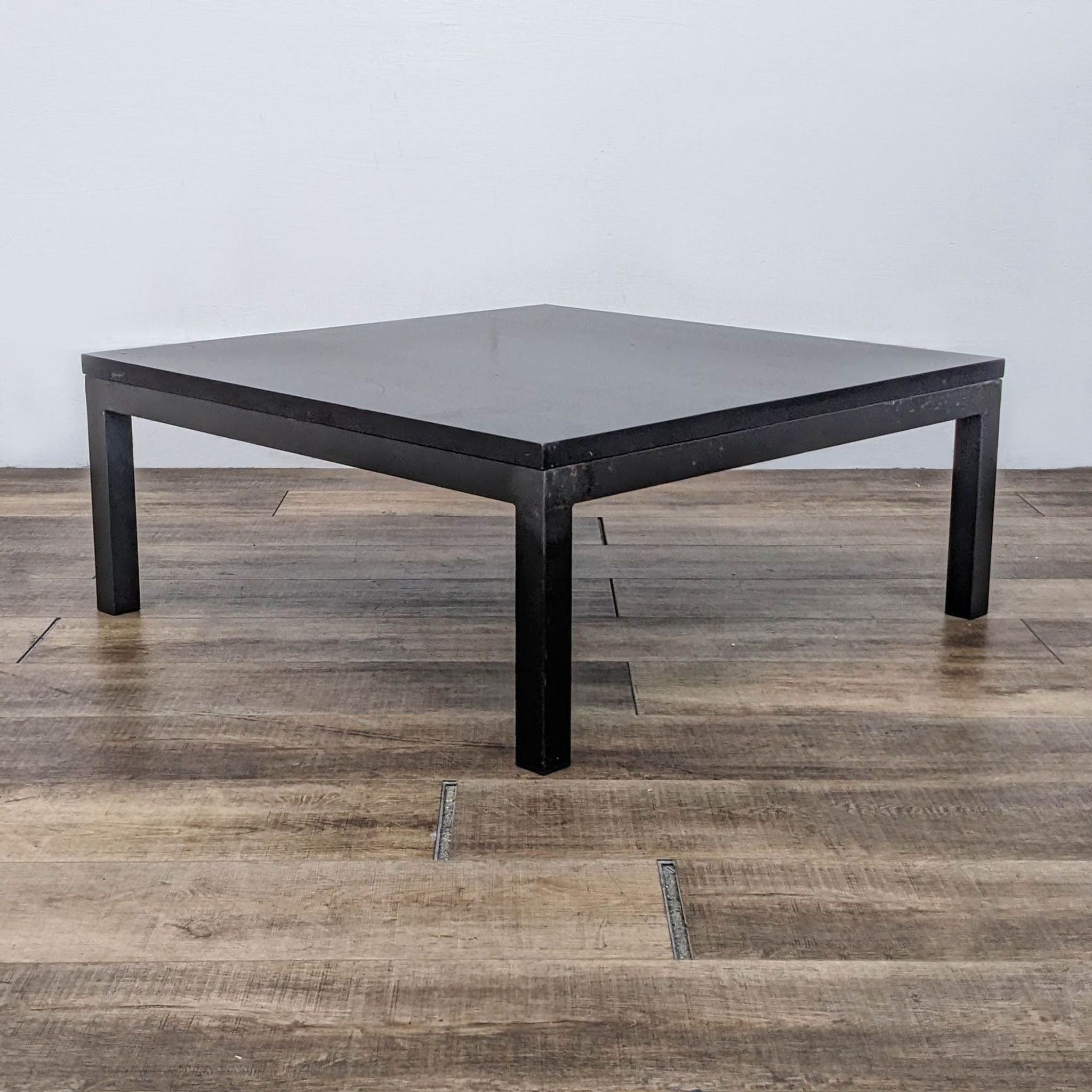 Room & Board Parsons style black coffee table on a wooden floor.