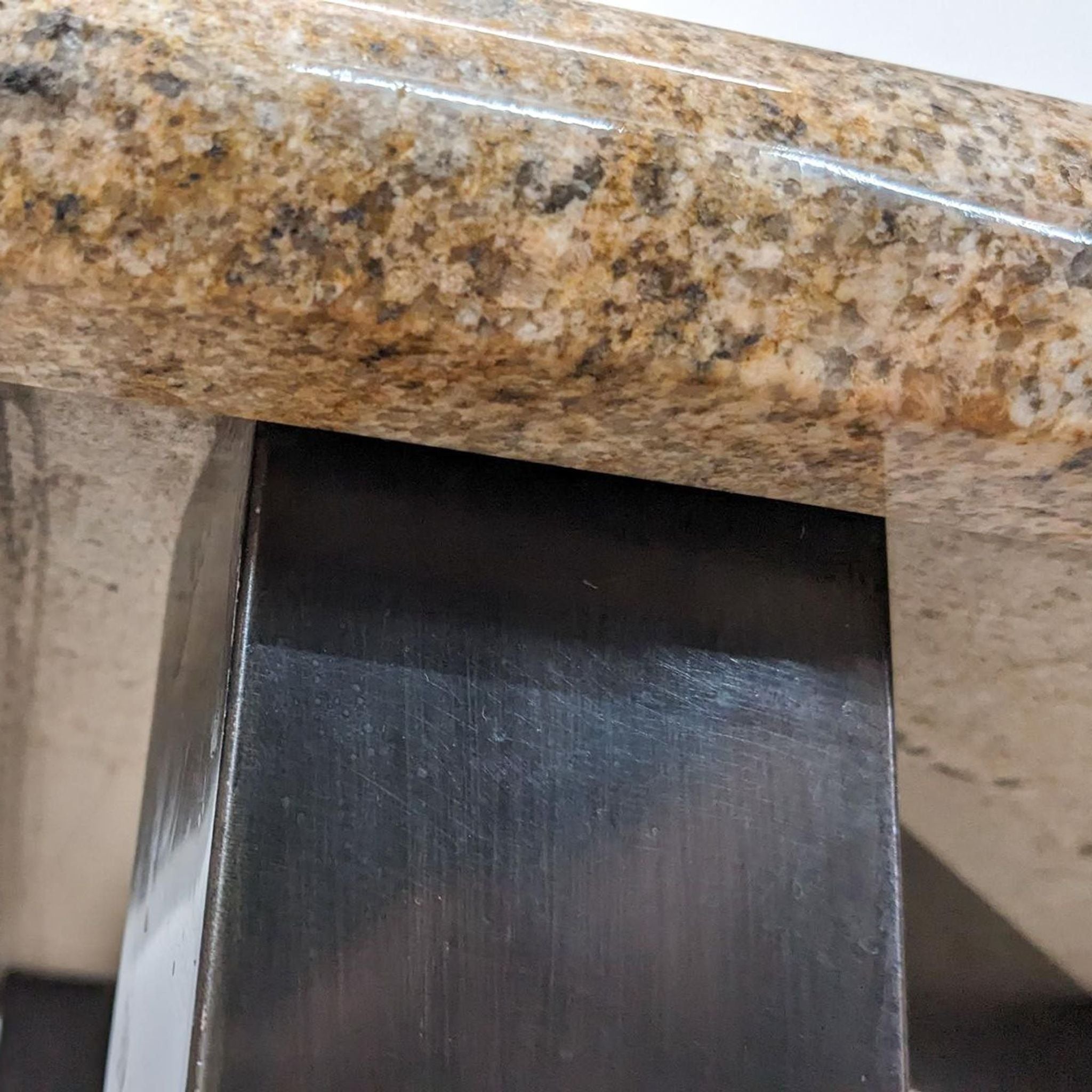 Close-up view of a Reperch coffee table showing the textured stone top and the metal base's detail.