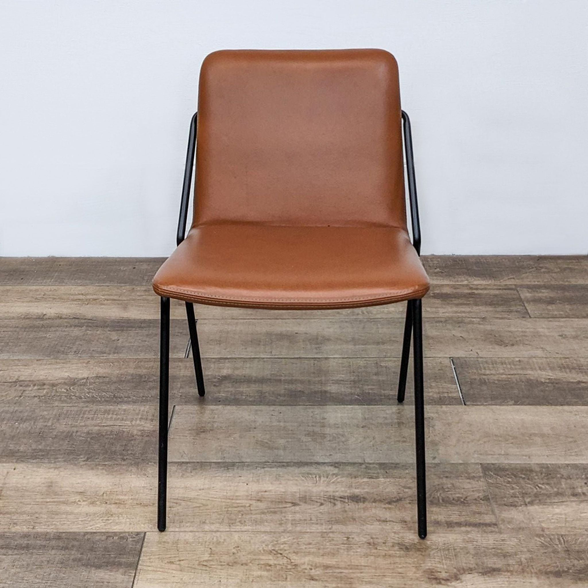 Reperch modern dining chair with angled back leg and vegan leather sling in frontal view on wooden floor.