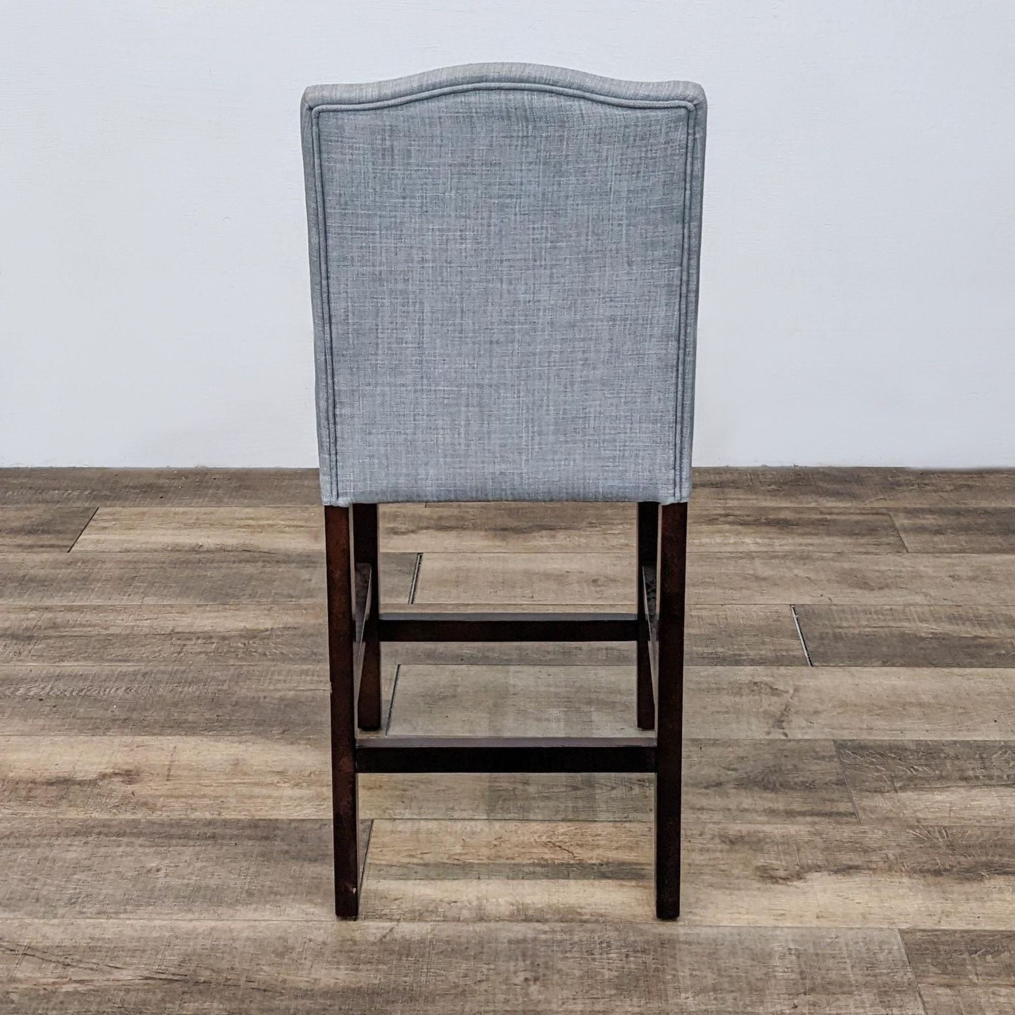 Reperch brand gray linen-look upholstered stool with nail head detailing and dark wood frame, viewed from the back.