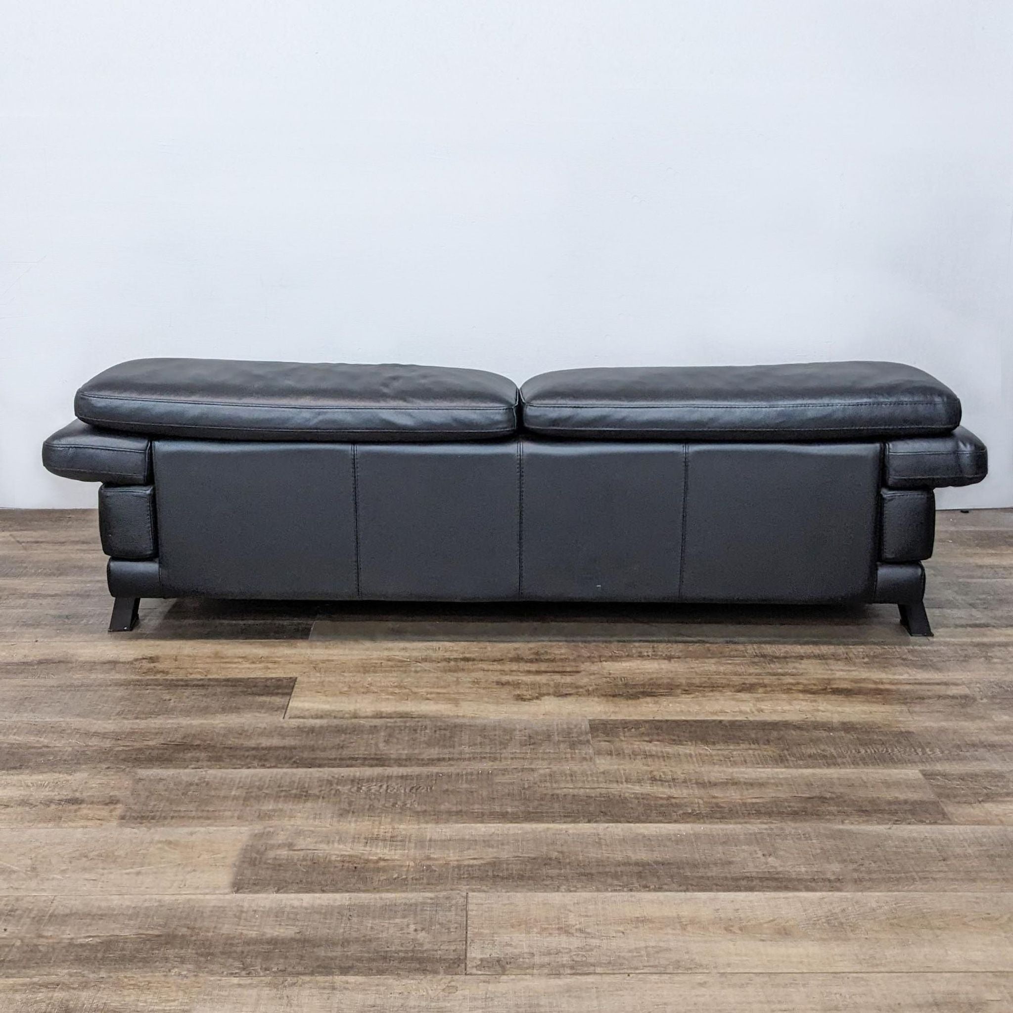 Rear view of Roche Bobois black leather loveseat, highlighting the low profile and metal side frame.