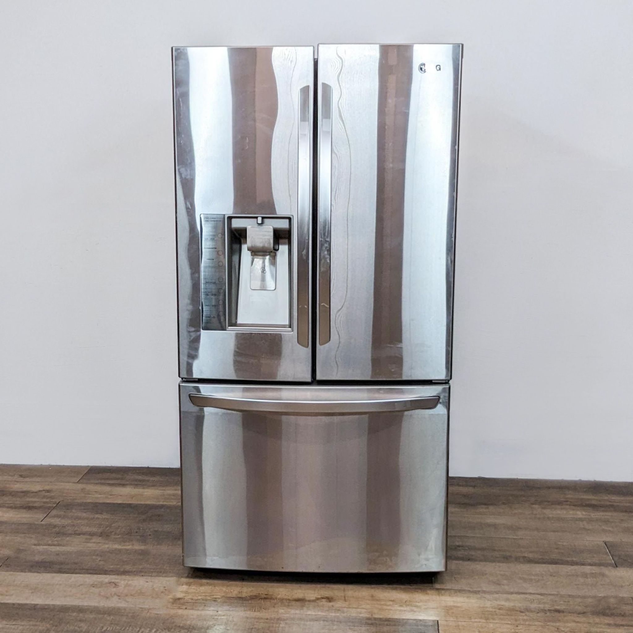 1. LG stainless steel French door refrigerator with water dispenser in a front-facing view, placed on a wooden floor.