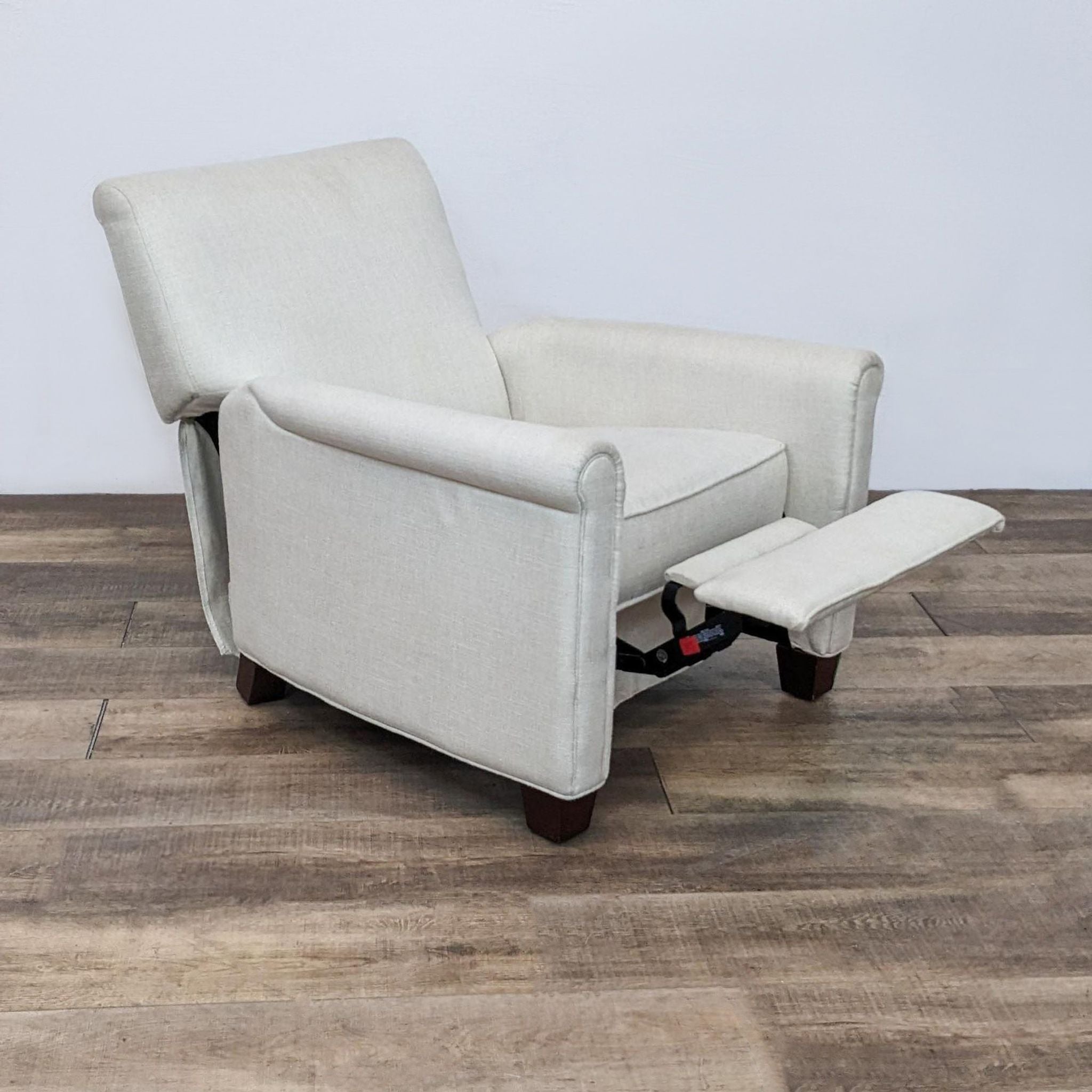 Beige Pottery Barn recliner chair with extended footrest, angled view on wooden floor.