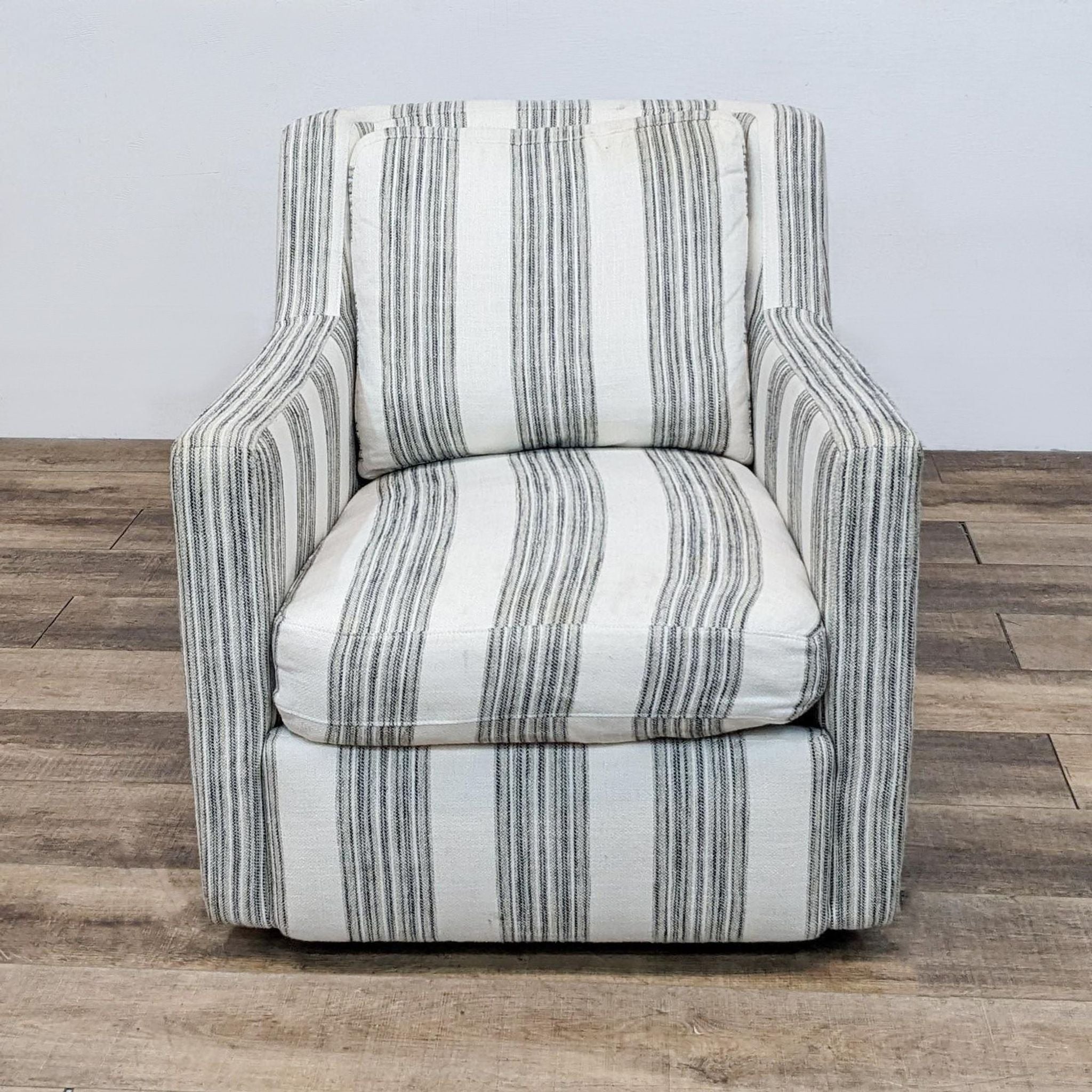 Ivory and black upholstered swivel chair by Comfort Design with striped pattern and removable cushions, shown from the front.