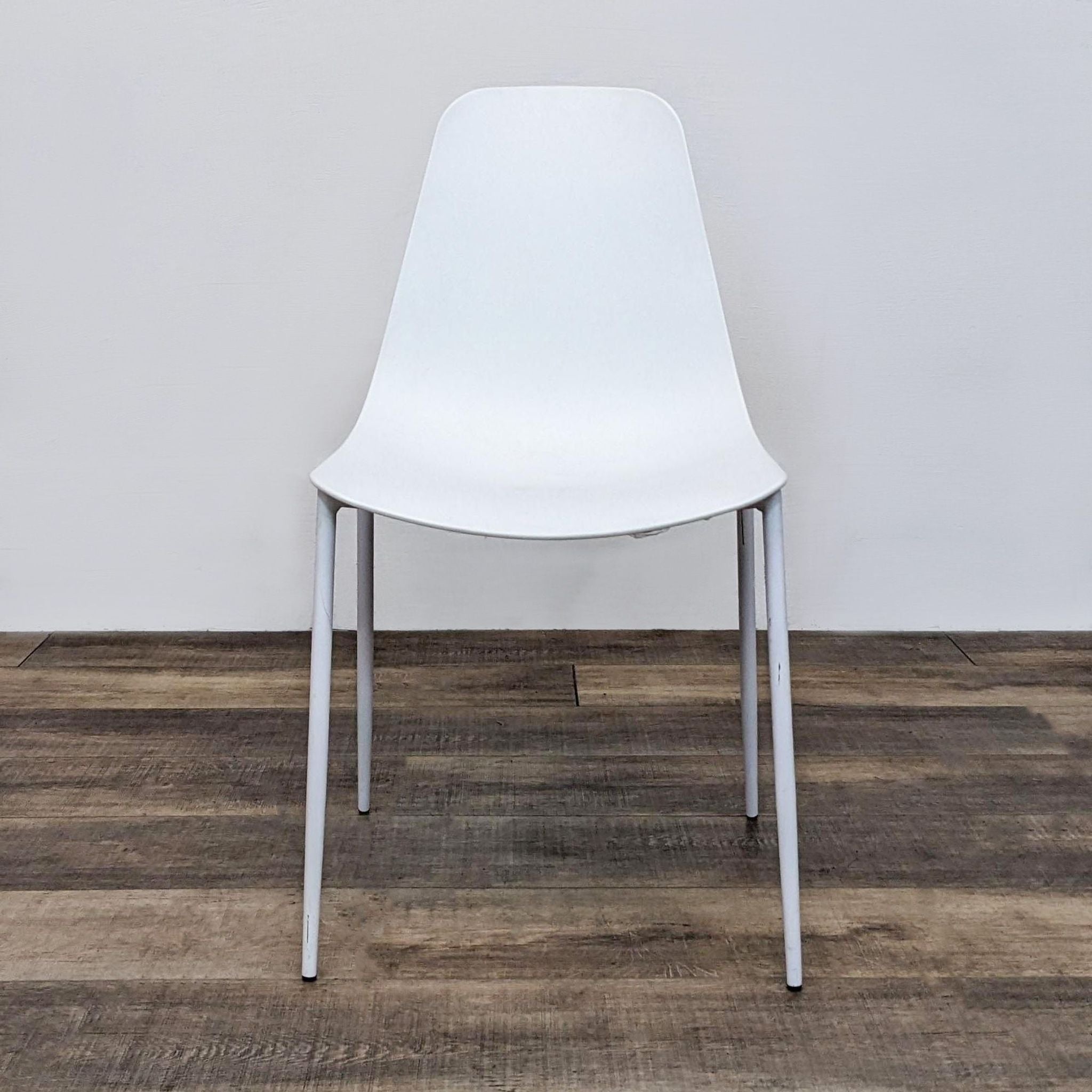 Reperch brand dining chair with scooped seat, powder-coated metal legs on wooden floor, front view.