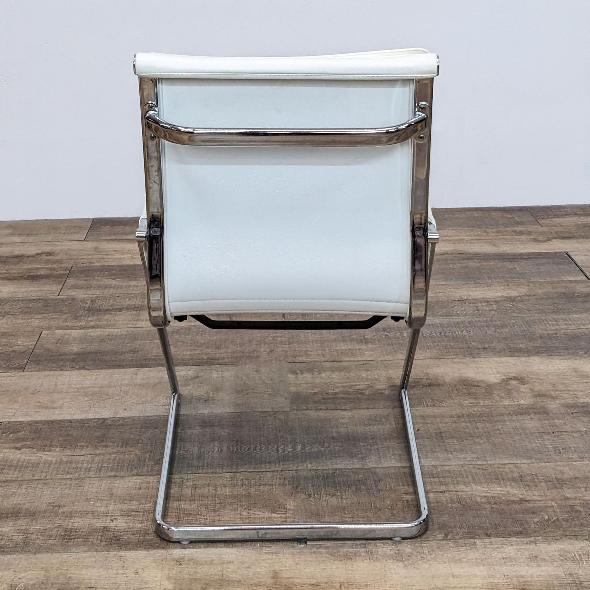 Zuo Modern brand chair with a white cushioned seat and backrest, featuring a chrome frame, displayed on a wooden floor.