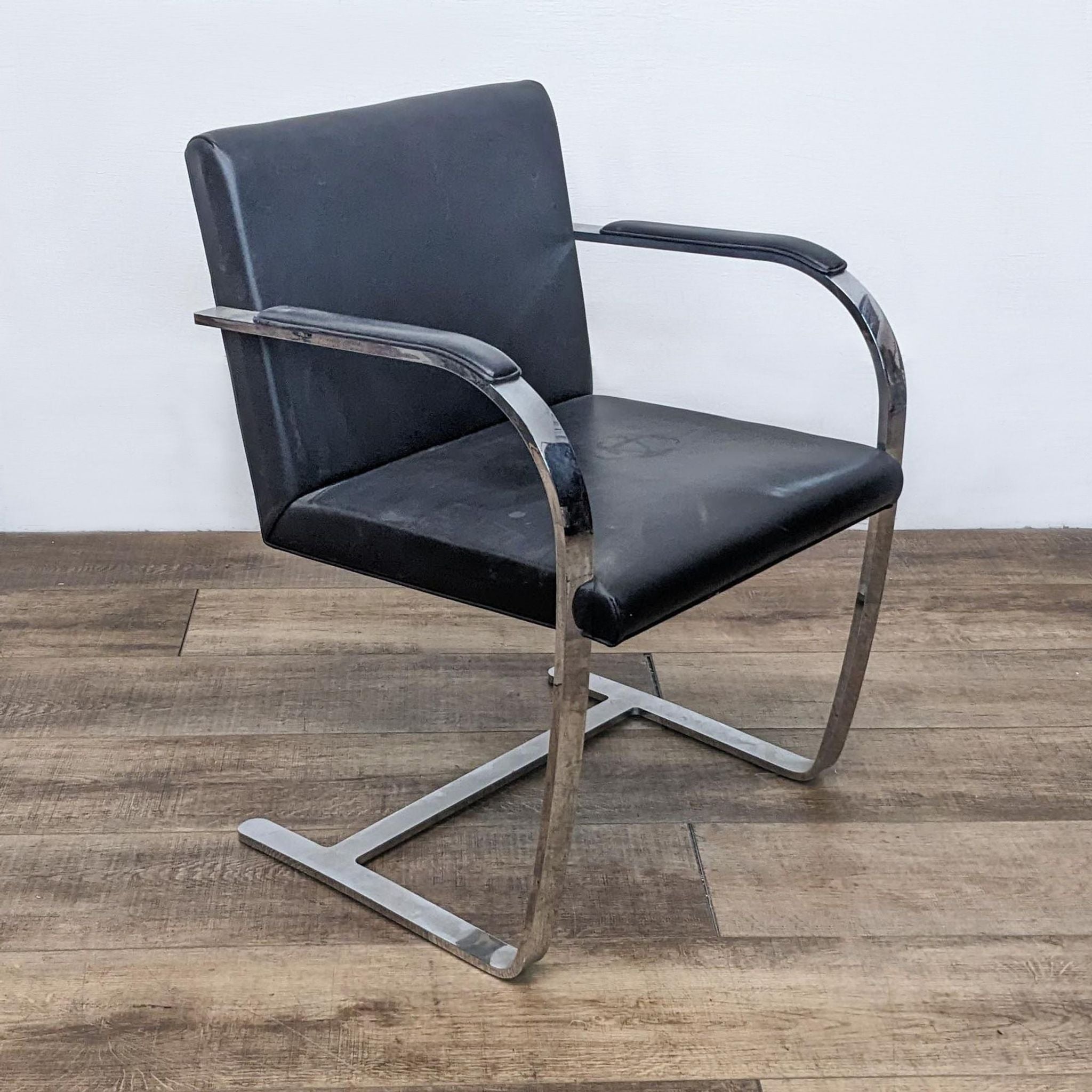 Alt text 2: Side angle of a Reperch stylish dining chair with continuous steel structure and padded black faux leather for comfortable seating.