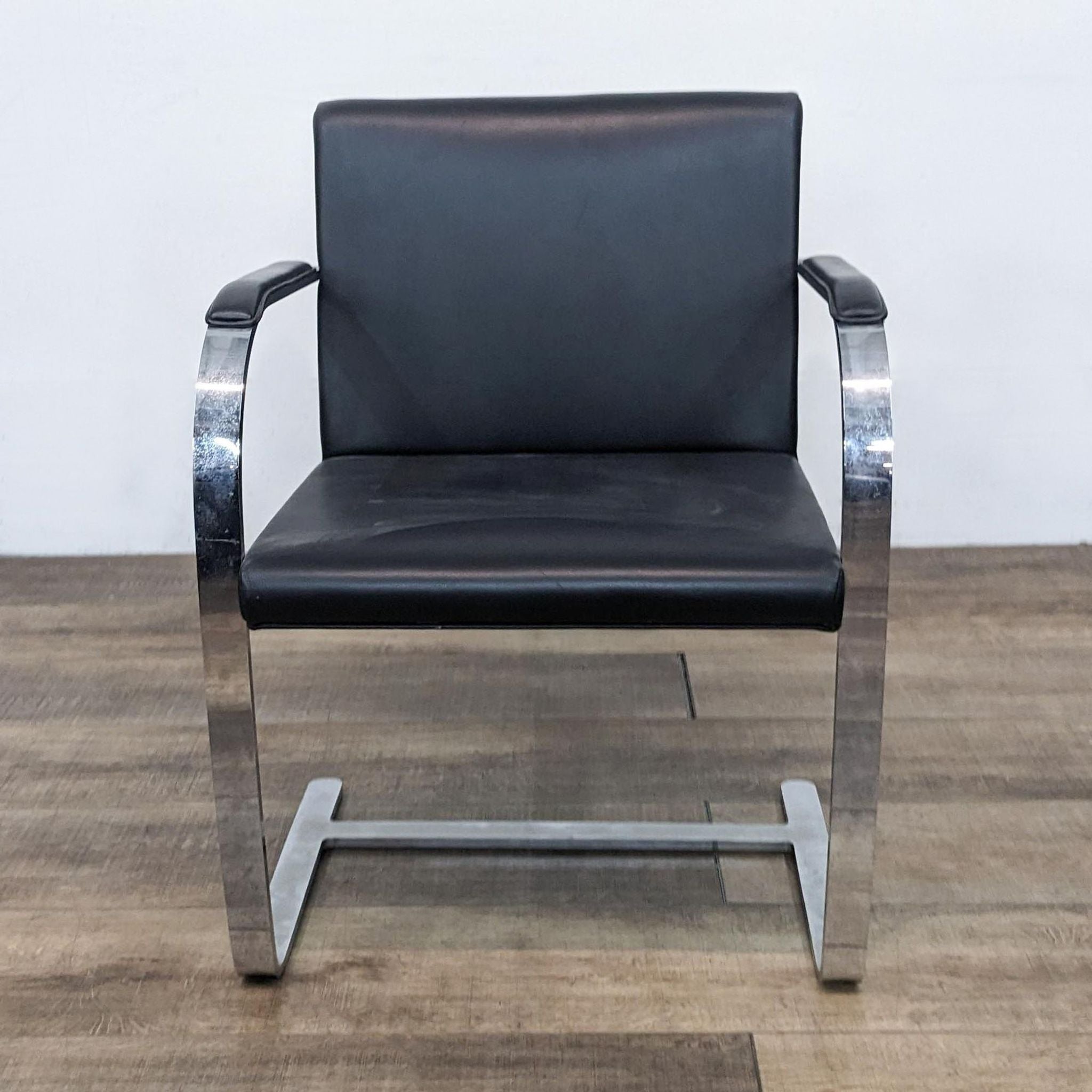 Alt text 1: A front view of a Reperch modern dining chair, featuring chrome steel legs and arms with a black faux leather cushioned seat.