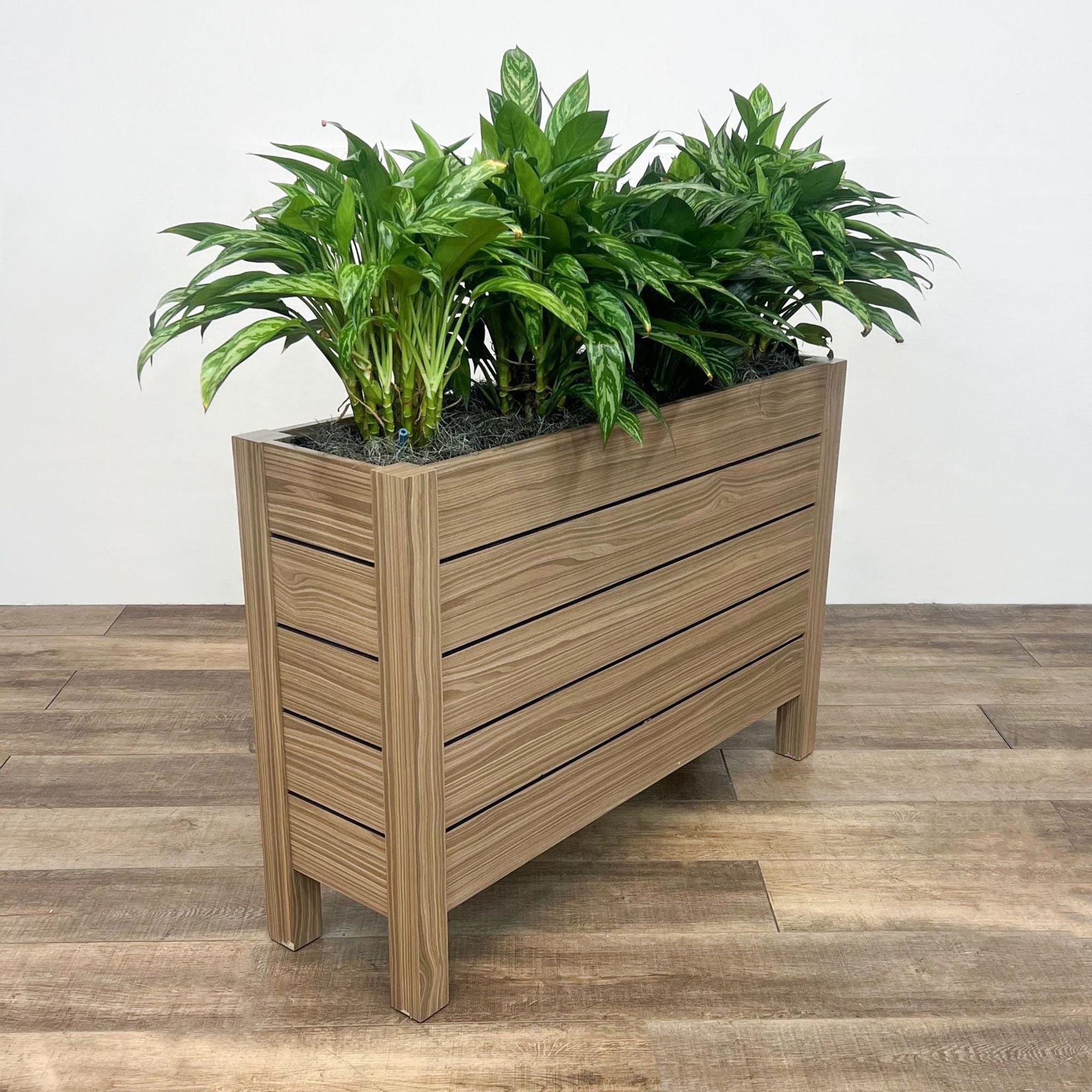 Vertical-oriented OFS Intermix wooden planter filled with lush greenery, on a laminate flooring.