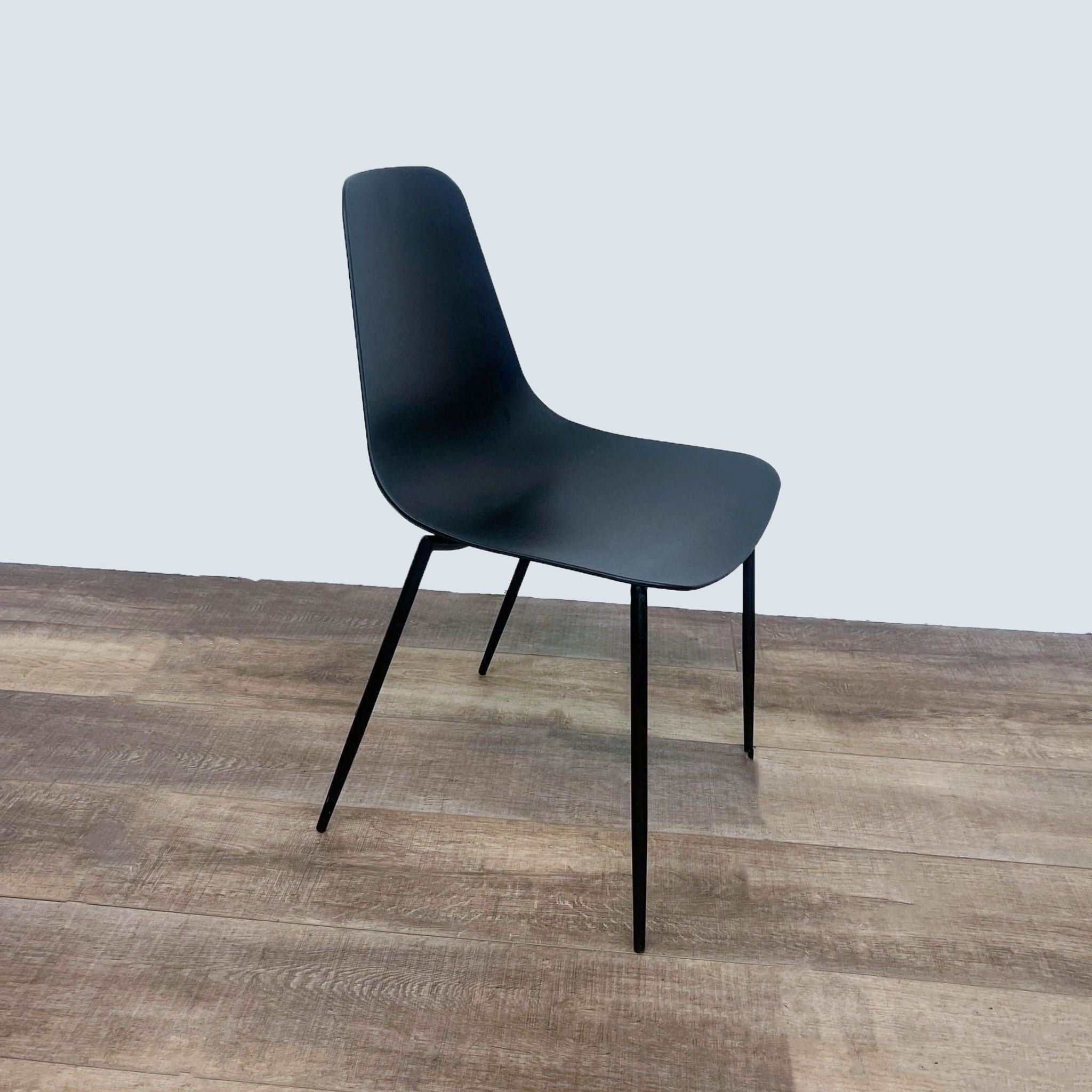 Reperch contemporary black dining chair, profile view showcasing contoured seat and tubular metal legs.
