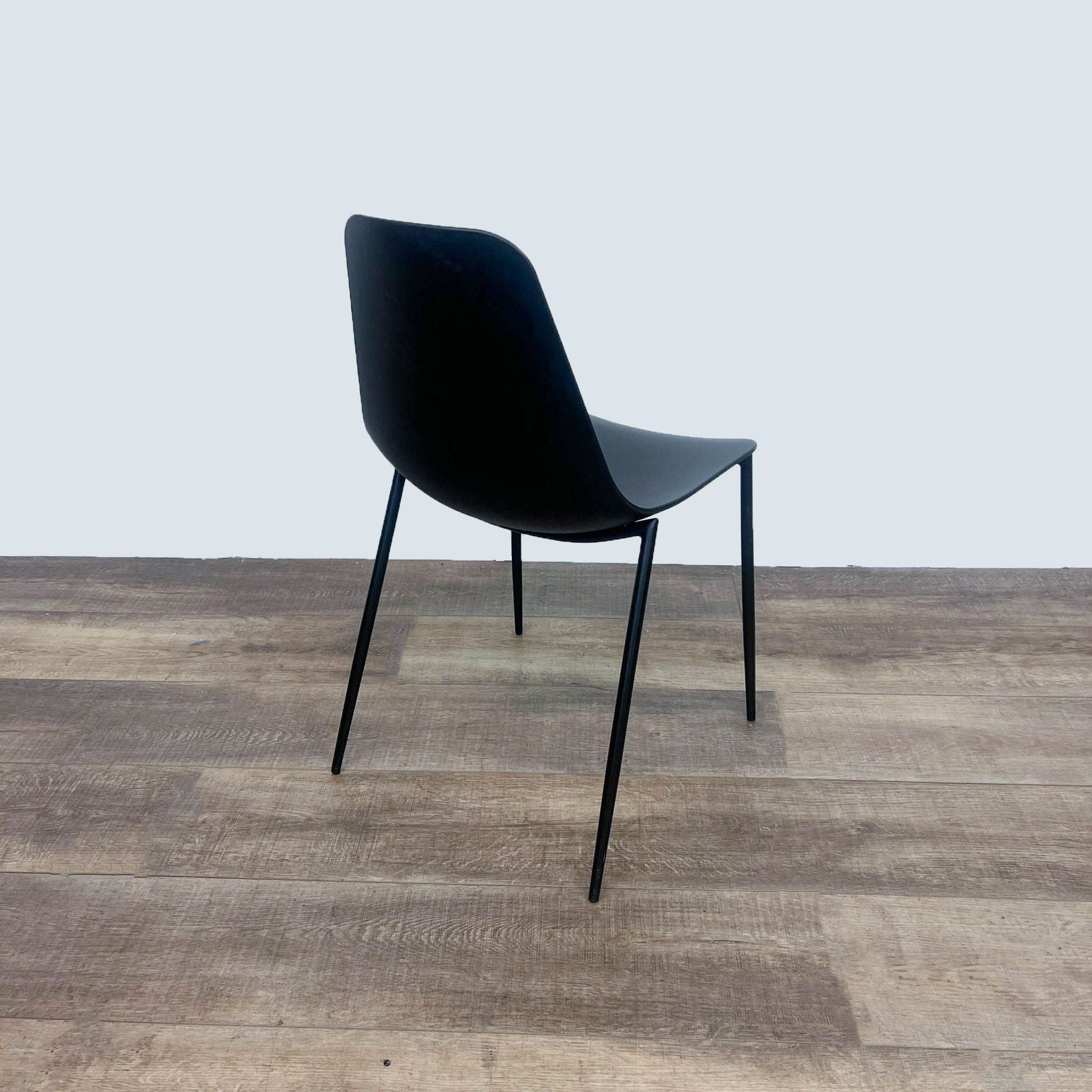 Black Reperch modern dining chair with a contoured plastic seat and metal legs on a wooden floor.