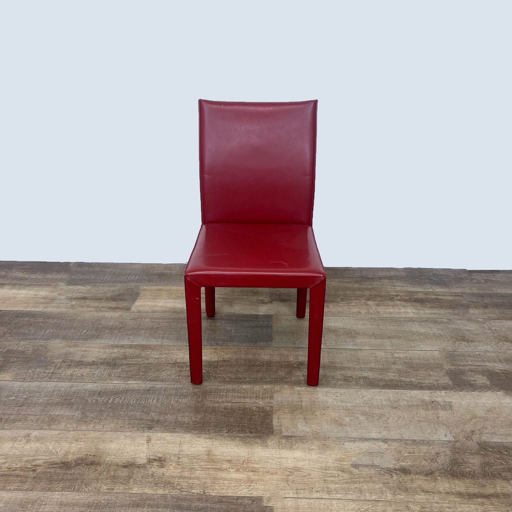 1. Maria Yee modern red leather dining chair with curved back on wooden floor.