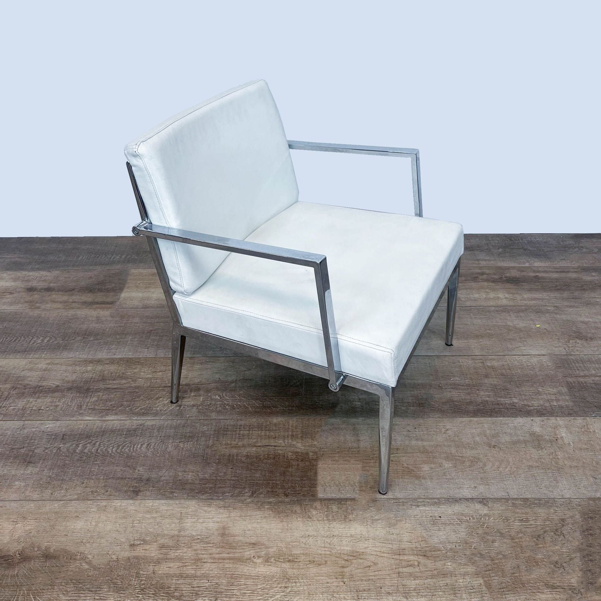 Reperch modern white leather armchair with chrome frame on wooden floor.