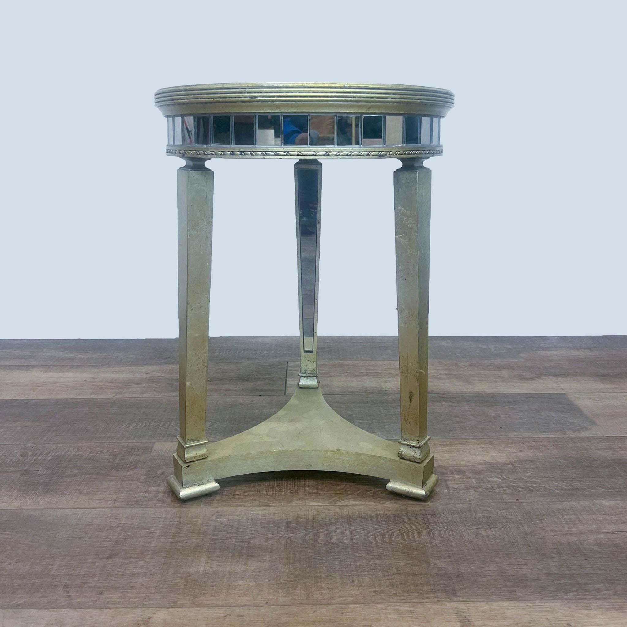 Reperch brand round console table with wood base and mirror top, side view on wooden flooring.