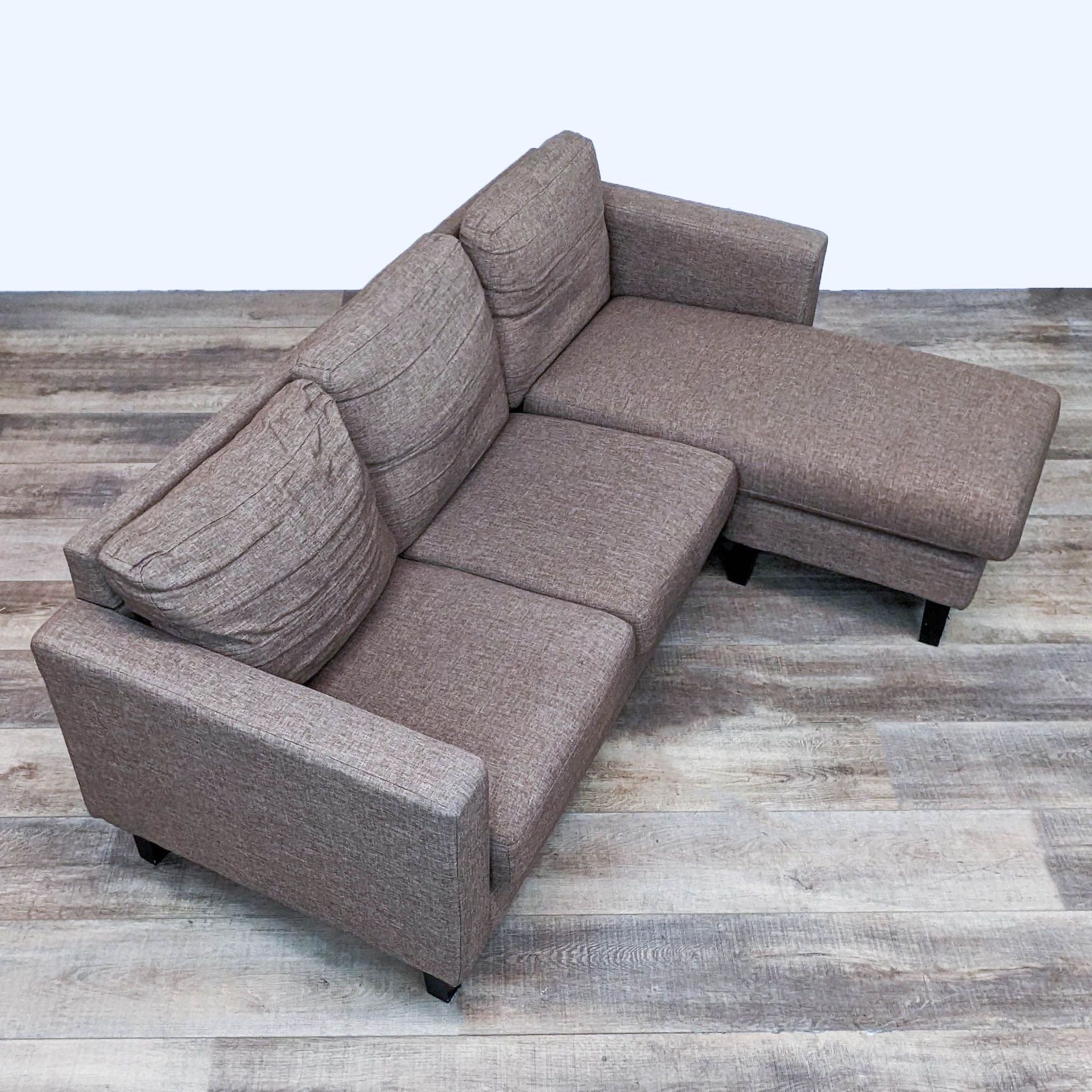 Brown Reperch sectional with reversible chaise, narrow arms, and dark finish feet in an indoor setting.